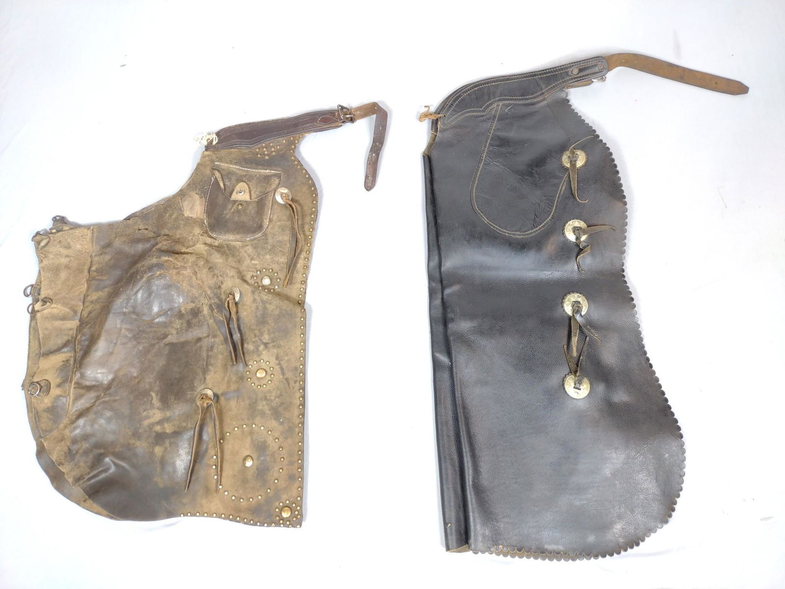 2 Pr Leather Chaps With Embellishments: Brown 21" wide X 30" long. Black 15-1/2" wide X 37" long. Some wear and losses. MG. IMPORTANT: Before bidding, please read the terms and conditions. When you registered for the auction you agreed to t