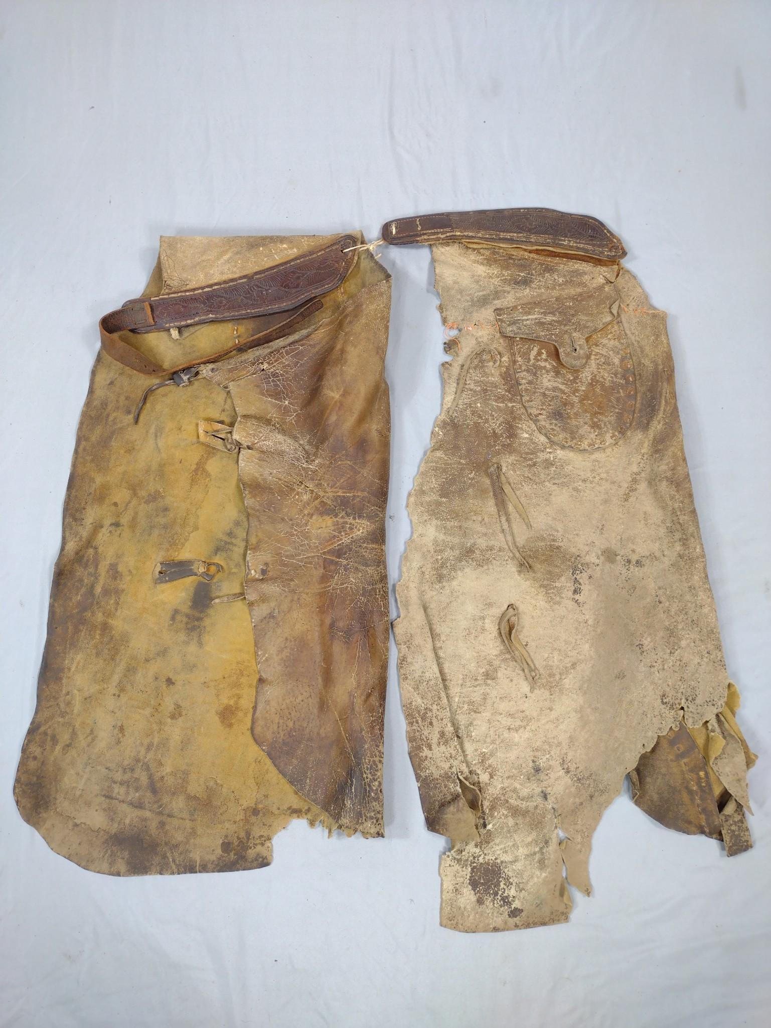 2 Pr Antique Leather Chaps: One pair with Tooled Leather belt. Some wear and losses. 16-1/2"-18" wide X 33"-37" long. MG. IMPORTANT: Before bidding, please read the terms and conditions. When you registered for the auction you a