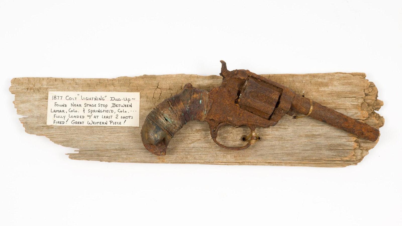 Colt 1877 "Lightning" Dug-Up, Mounted on Old Board: Serial Number: NSN (Rusted beyond recognition) Design: Dug-up relic Colt Lightning 1877. 4-1/2" barrel originally hade an unloading rod and housing, now missing. Remains of cartridges still in cylinde