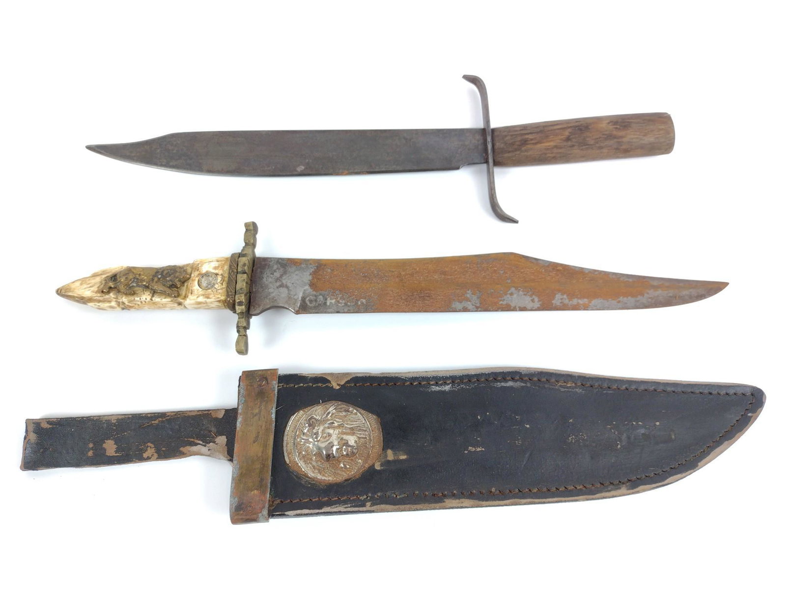 Two Bowie Knives: One unmarked with wood handle. One with bone handle an golden lion courier guard (Denver) decoration to leather sheath. Also has rust. Overall 15" to 15-1/2" long. MG. IMPORTANT: Before bidding, pleas