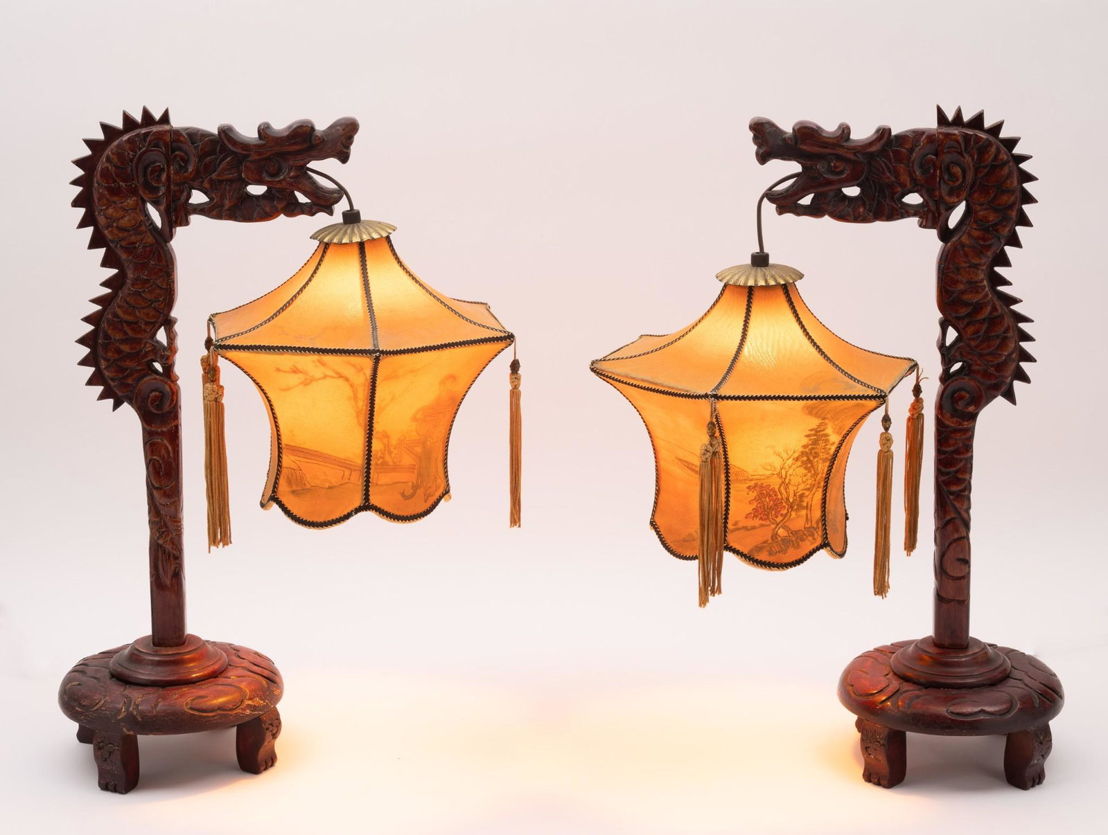 Pair of Dragon Pendant Lights: DESCRIPTION: Pair of dragon pendant lights. Wood carved dragons with pendant lights suspended from dragon mouths. Fabric shades with hand painted scenes, most visible when the lights are on. Each poin