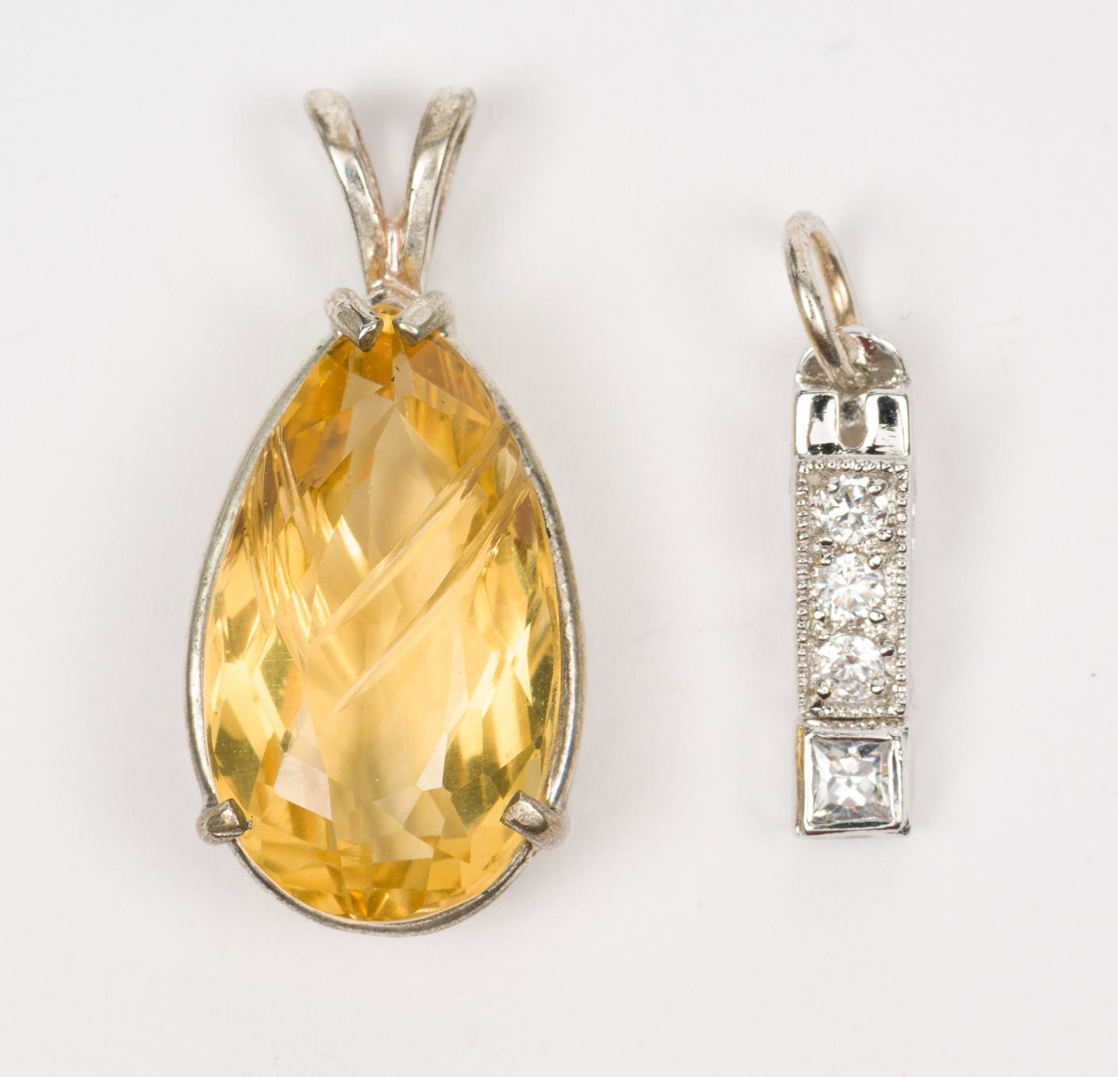 2 Silver Gemstone Pendants: CZ pendant marked 925, 3/4" long. Unmarked silver pendant set with 11.8 carat (13mm x 22mm) etched pear cut citrine. 1-1/4" long. MH/EK IMPORTANT: Before bidding, please read the terms and conditions.