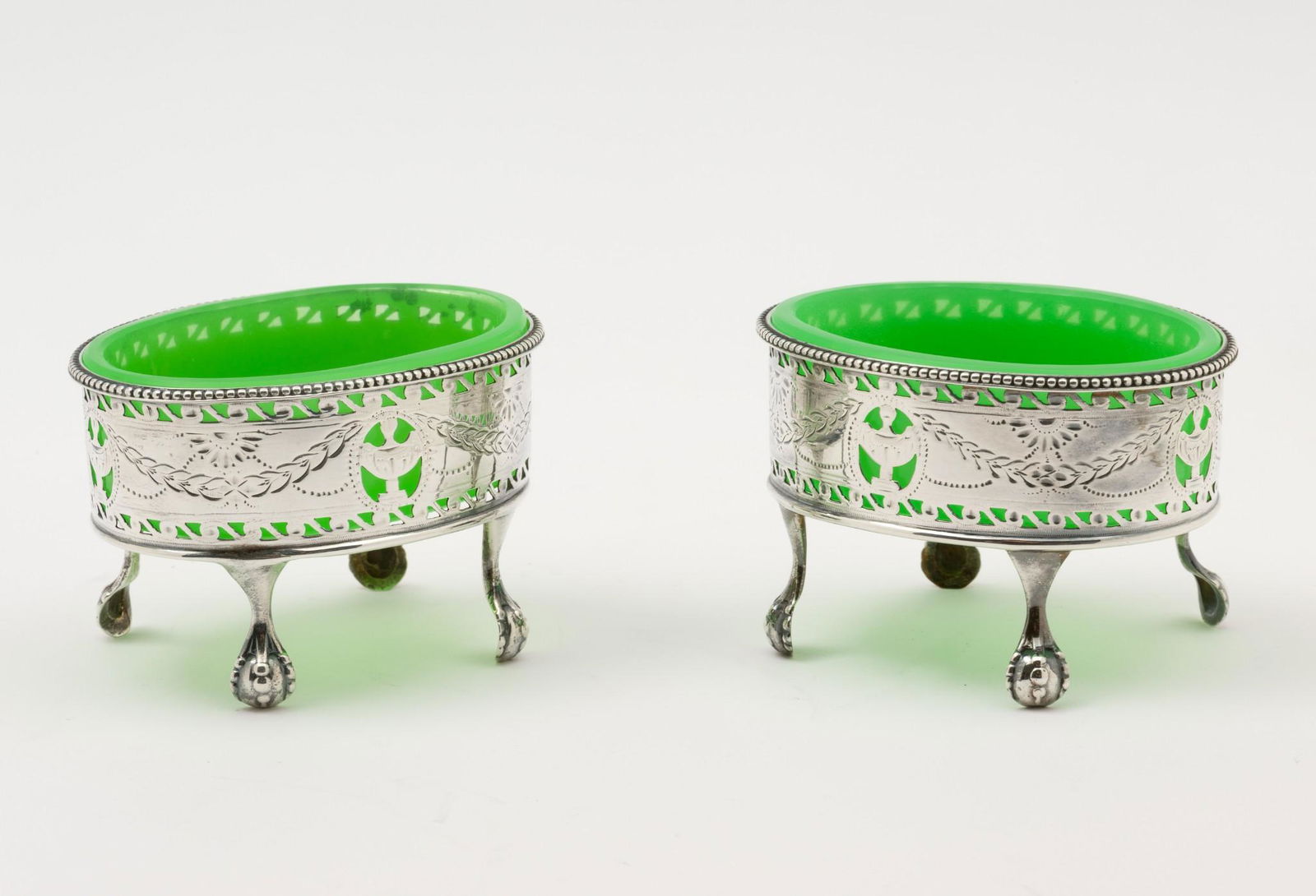 Pair of 1782 Hester Bateman Open Salts: DESCRIPTION: Pair of Hester Bateman sterling open salts with green glass insert. Urn and swag design with beaded rim and claw and ball feet. Each monogrammed to one side. Each marked for Hester Batema