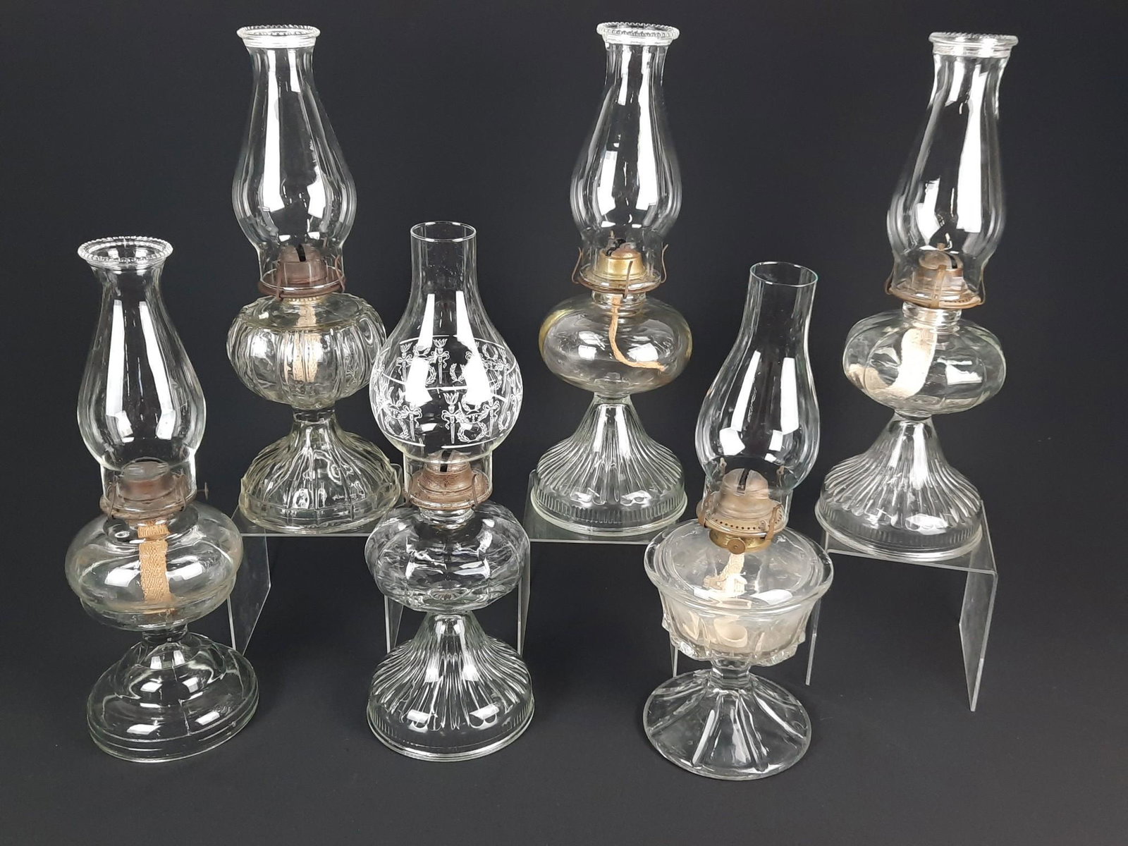 6 Glass Oil Lamps: 17-1/2" to 18-1/2" high. LR IMPORTANT: Before bidding, please read the terms and conditions. When you registered for the auction you agreed to these terms and will be required to comply with them.