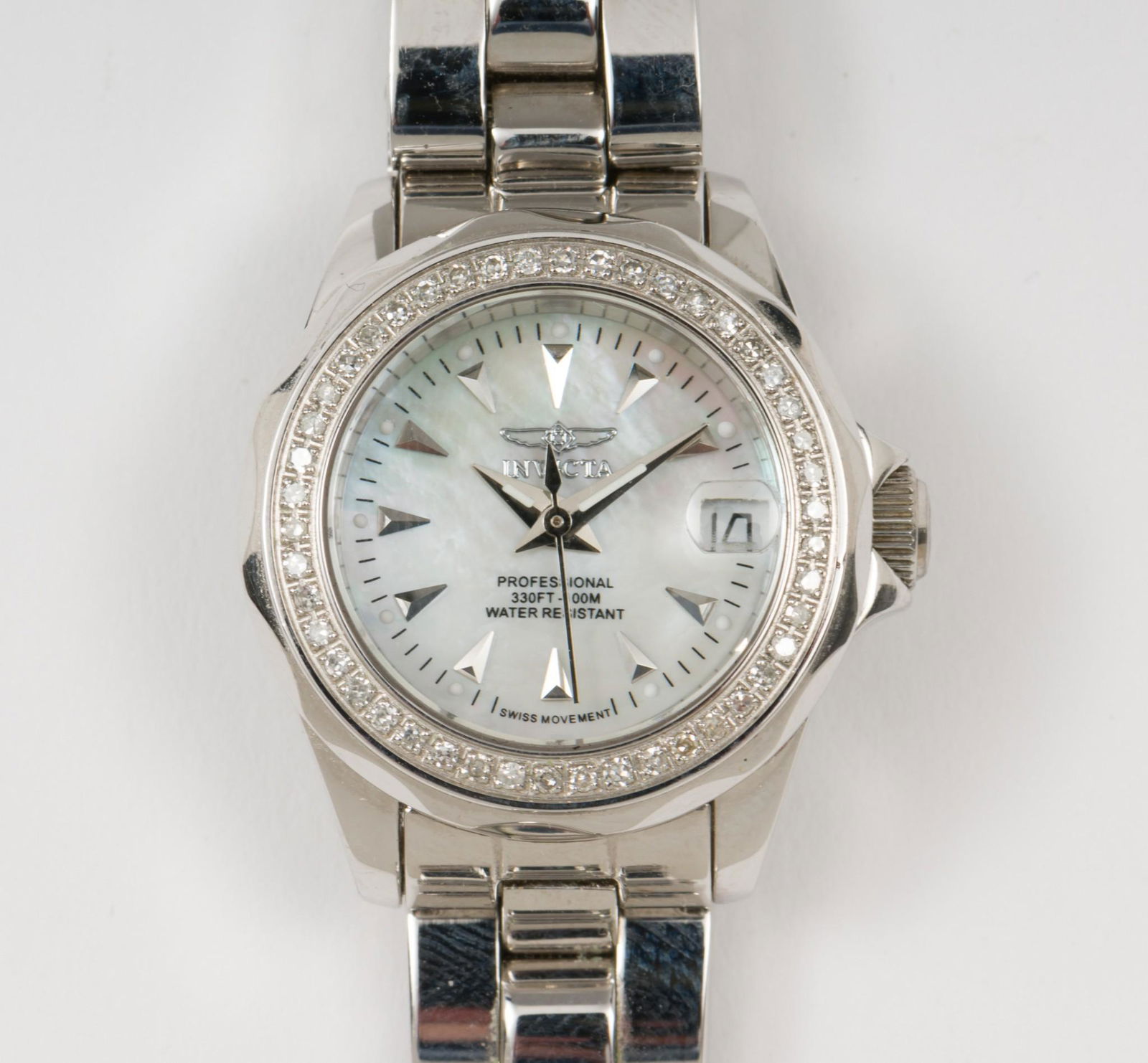 Ladies Invicta Diamond Dial Wristwatch in OB: Swiss movement in stainless steel case water resistant to 100 meters. Mother of pearl dial with date. Diamond set bezel. In original box. 1-1/8" lug to lug on adjustable bracelet. Running. MH. IMPORTA