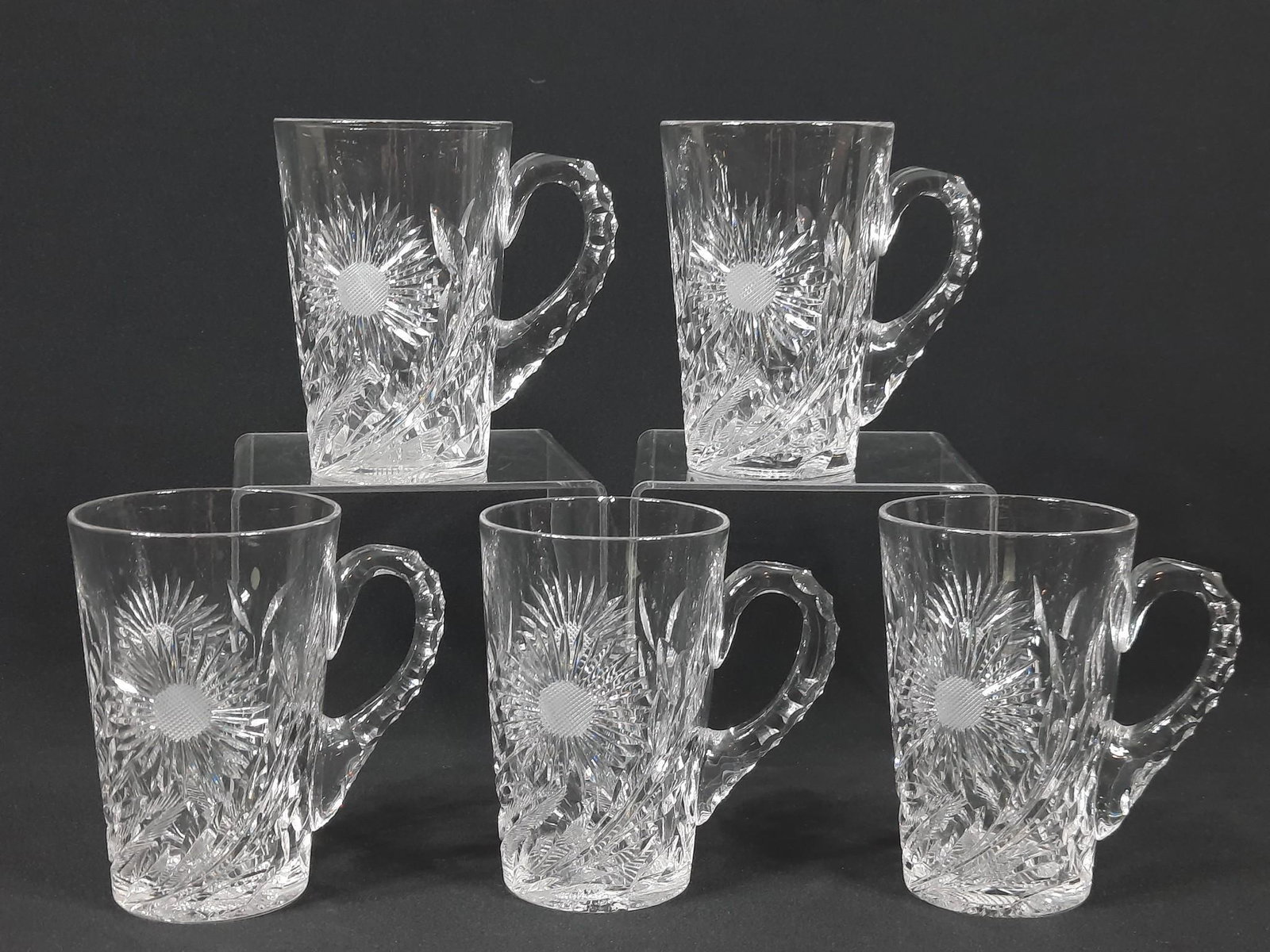 5 Cut Glass Mugs: Unmarked. 4-1/2" wide x 4-3/4" high. One with chip to rim. LR IMPORTANT: Before bidding, please read the terms and conditions. When you registered for the auction you agreed to these terms and will be