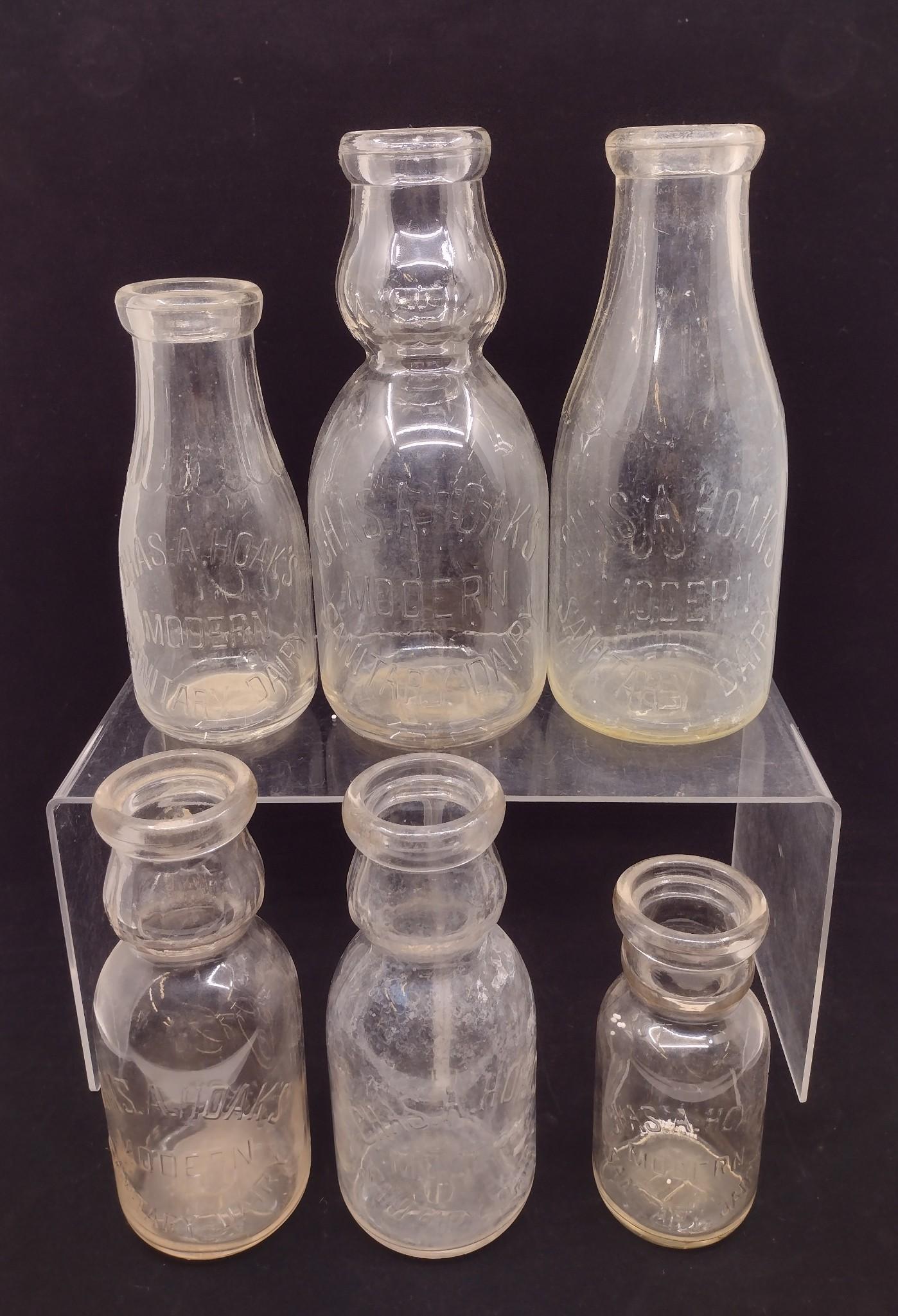 5 Ryder's Dairy Lemoyne, PA Milk Bottles: Includes round one quart bottle with embossed block lettering, (3) one quart bottles with embossed cursive lettering, and one quart bottle with brown lettering. 8-3/4" to 9-1/2" high. Some losses / fa