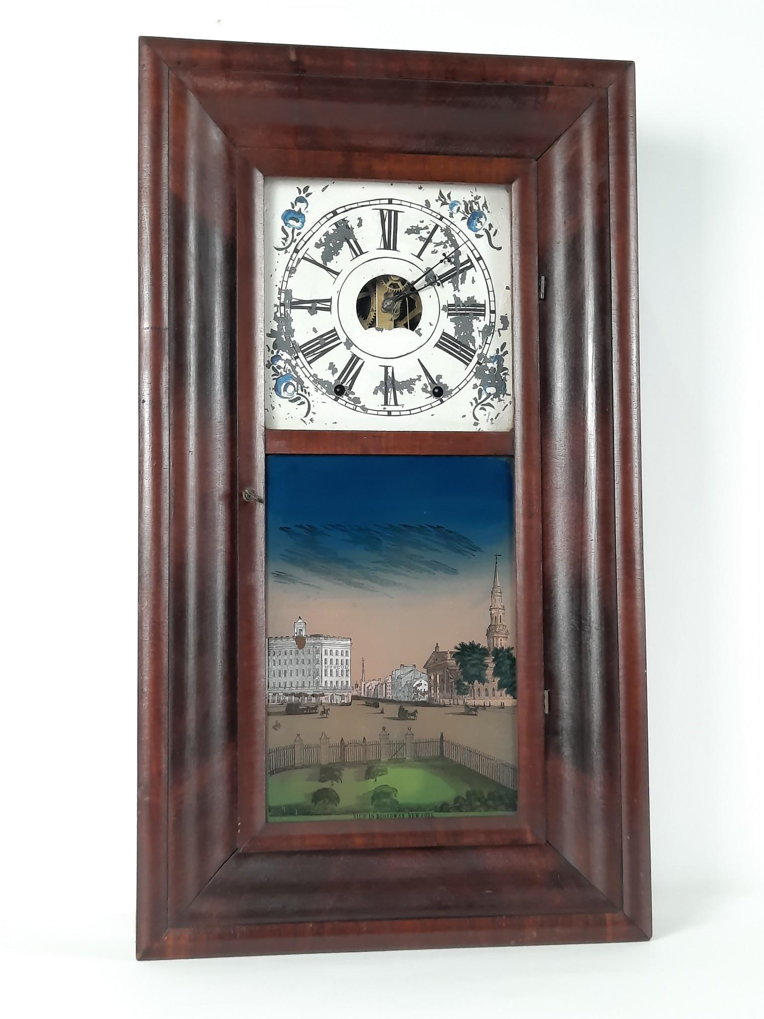 View of Broadway, NY Ogee Clock: Working. 16-1/2" wide x 4-1/2" deep x 29-1/2" high. Manufacturers interior label with losses. Veneer loss to right side at base. LR IMPORTANT: Before bidding, please read the terms and conditions. Whe