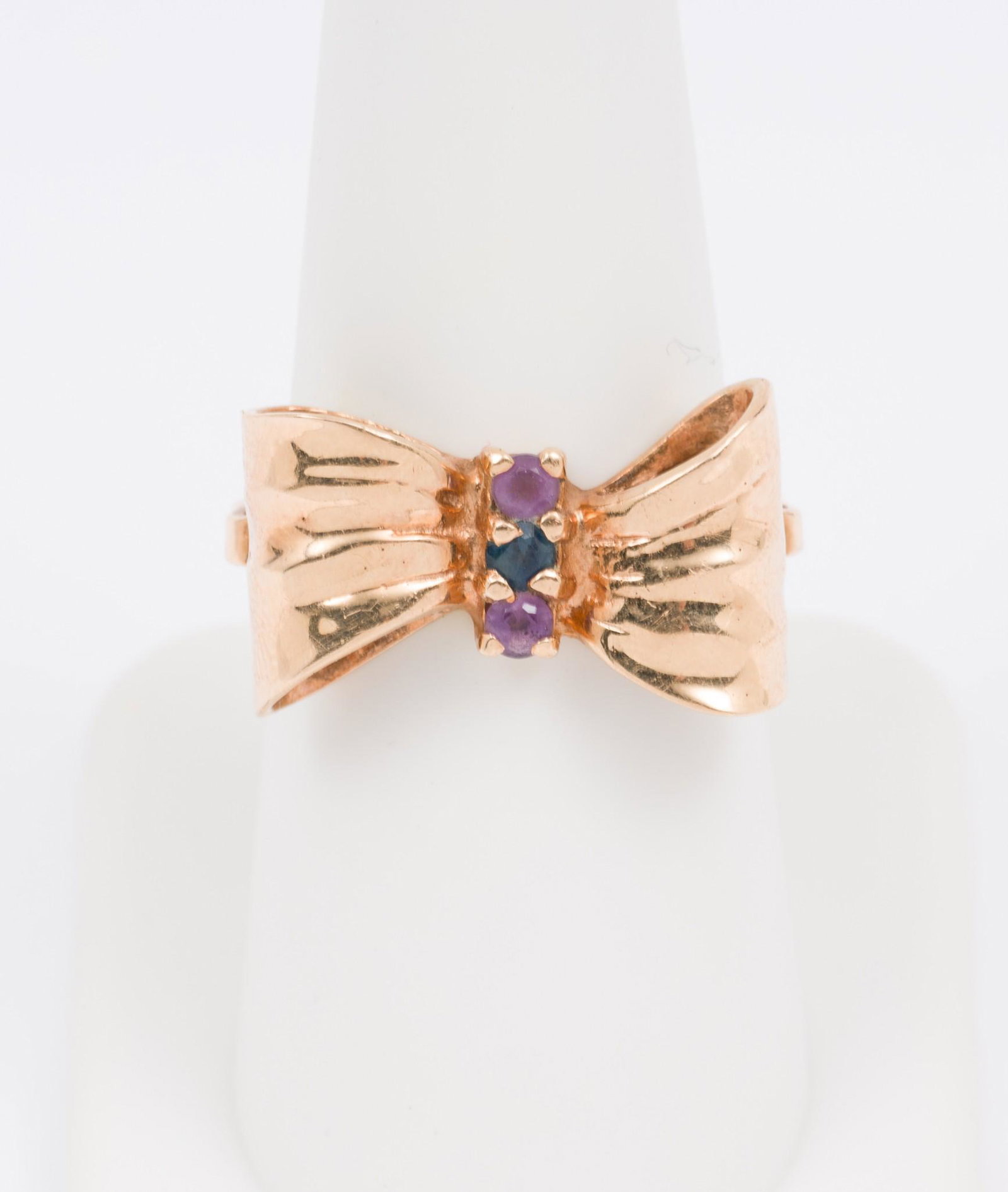 18K Gold Bow Ring: Vintage bow form ring tested 18k gold. Set with sapphire and two amethysts, each approximately .03 carat. Size 7, 1/2" wide. 3.1 dwt. MH/EK IMPORTANT: Before bidding, please read the terms and conditi