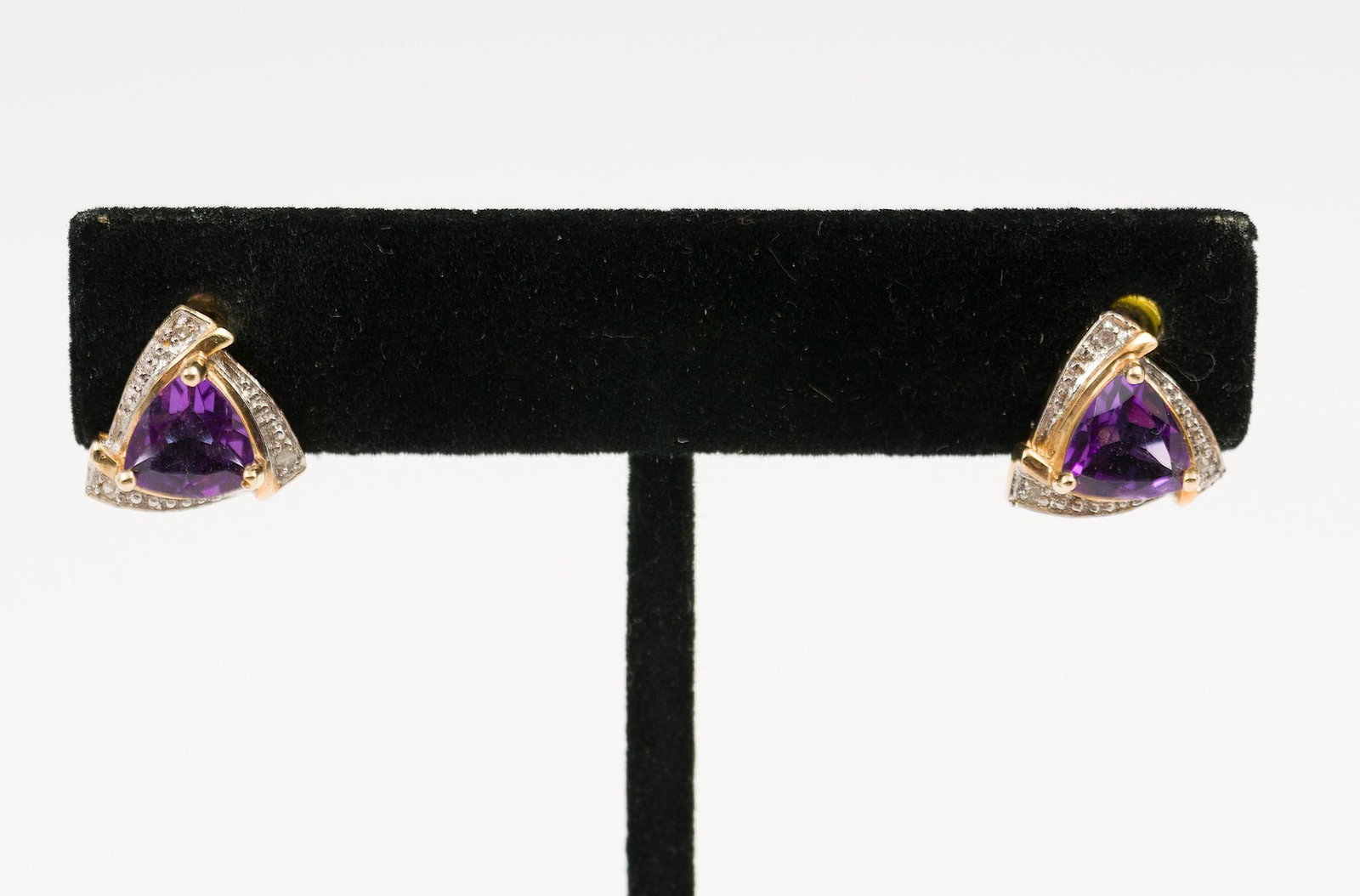 Pair of 14K Gold & Amethyst Earrings: Marked 14k gold pierced earrings each set with approximately .87 carat trillion cut amethyst and three diamond chips. 3/8" long. 1.5 dwt. MH/EK IMPORTANT: Before bidding, please read the terms and con