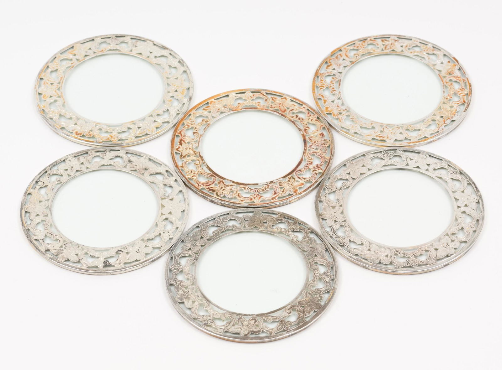 6 Antique Sterling & Glass Coasters: Sterling coasters with floral border around glass. Marked Sterling. 3" diameter. MEG IMPORTANT: Before bidding, please read the terms and conditions. When you registered for the auction you agreed to