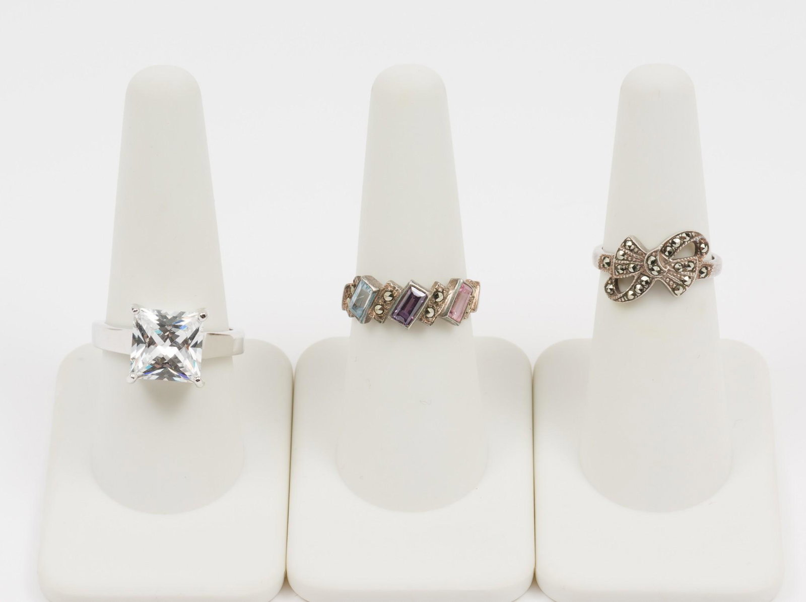 3 Sterling Rings: Includes sterling princess cut CZ, sterling with marcasite in bow form, and sterling with marcasite, blue topaz, amethyst, and pink topaz. Sizes 5-1/2 to 9. 1/4" to 1/2" wide. MEG/EK IMPORTANT: Before