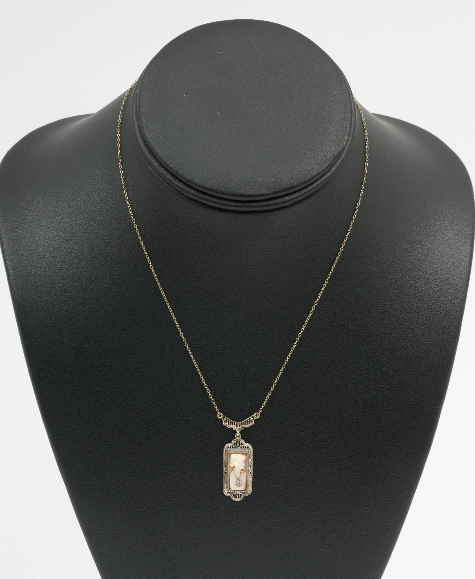 10K White Gold Cameo Necklace: Marked 10k chain, filigree pendant section set with carved cameo with inset .01 carat single cut diamond. 1.9 dwt. 15" long chain with 3/4" wide pendant. MEG/EK IMPORTANT: Before bidding, please read 
