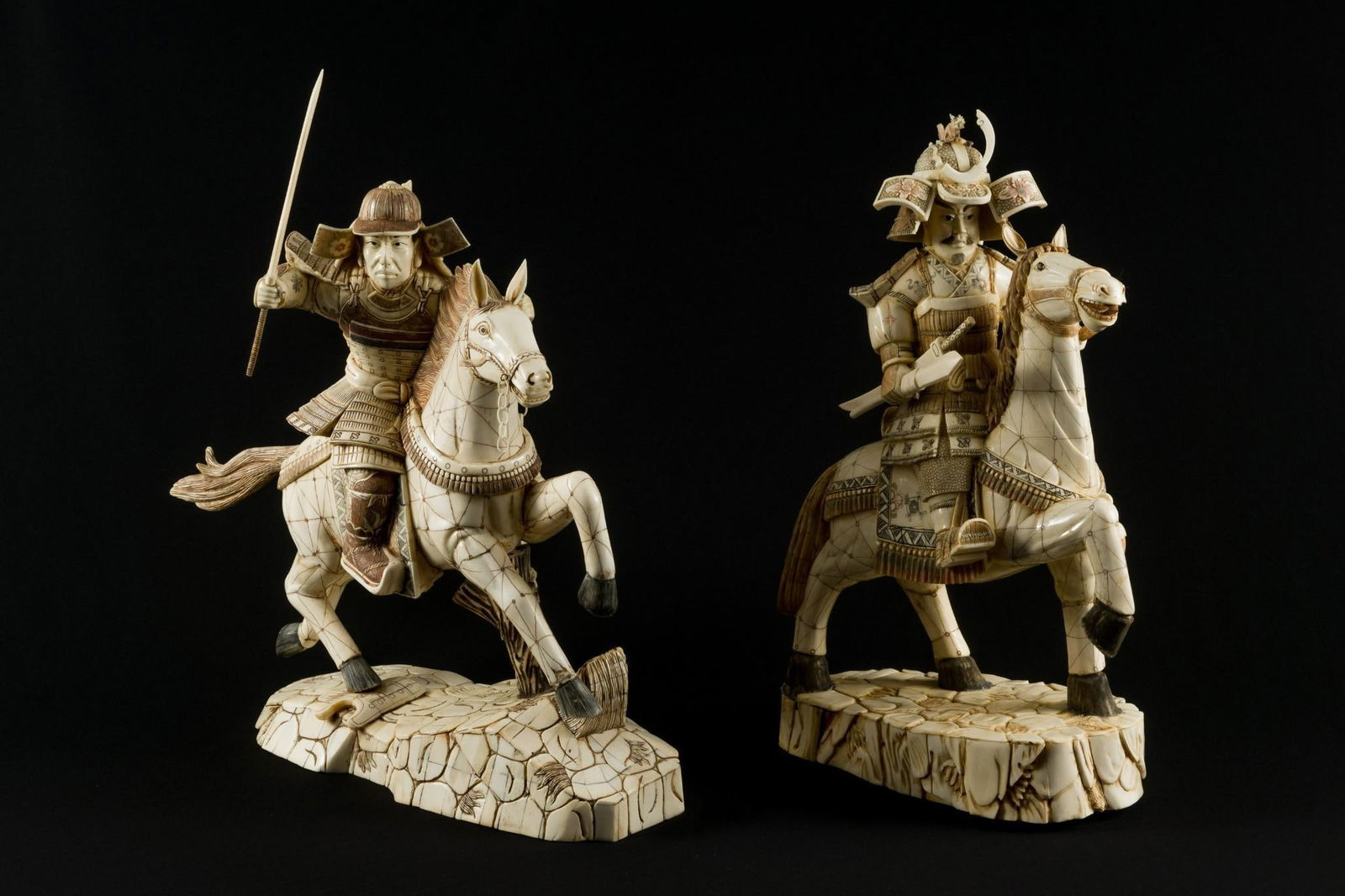 Pair Of 24" Carved Bone Samurai On Horseback: DESCRIPTION: Pair of two samurai warriors on horseback. Unmarked, with removable weapons. MEASUREMENTS: Raised sword statue 23-1/2" high x 16-1/2" wide x 9" deep. Other statue 22" high x 13-1/2" wide