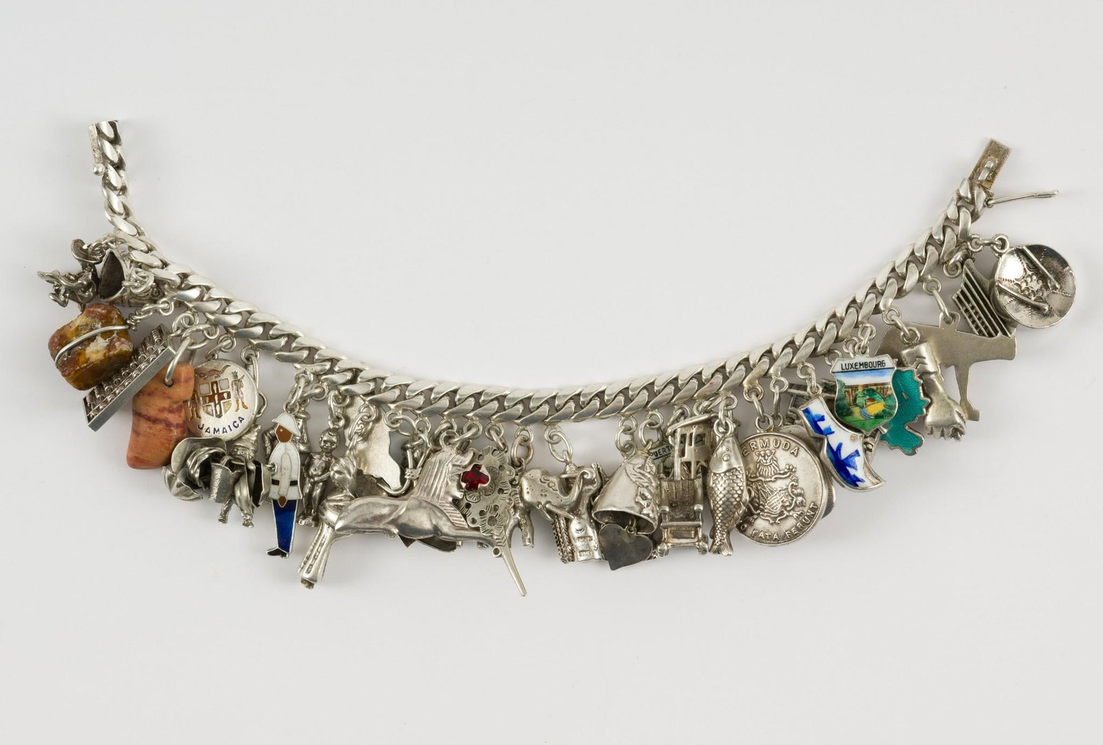 Sterling Charm Bracelet: Sterling charm bracelet with 34 charms. Marked sterling. 1-1/2" wide x 7-1/2" long. 2.03 ozt total. No condition issues. MEG