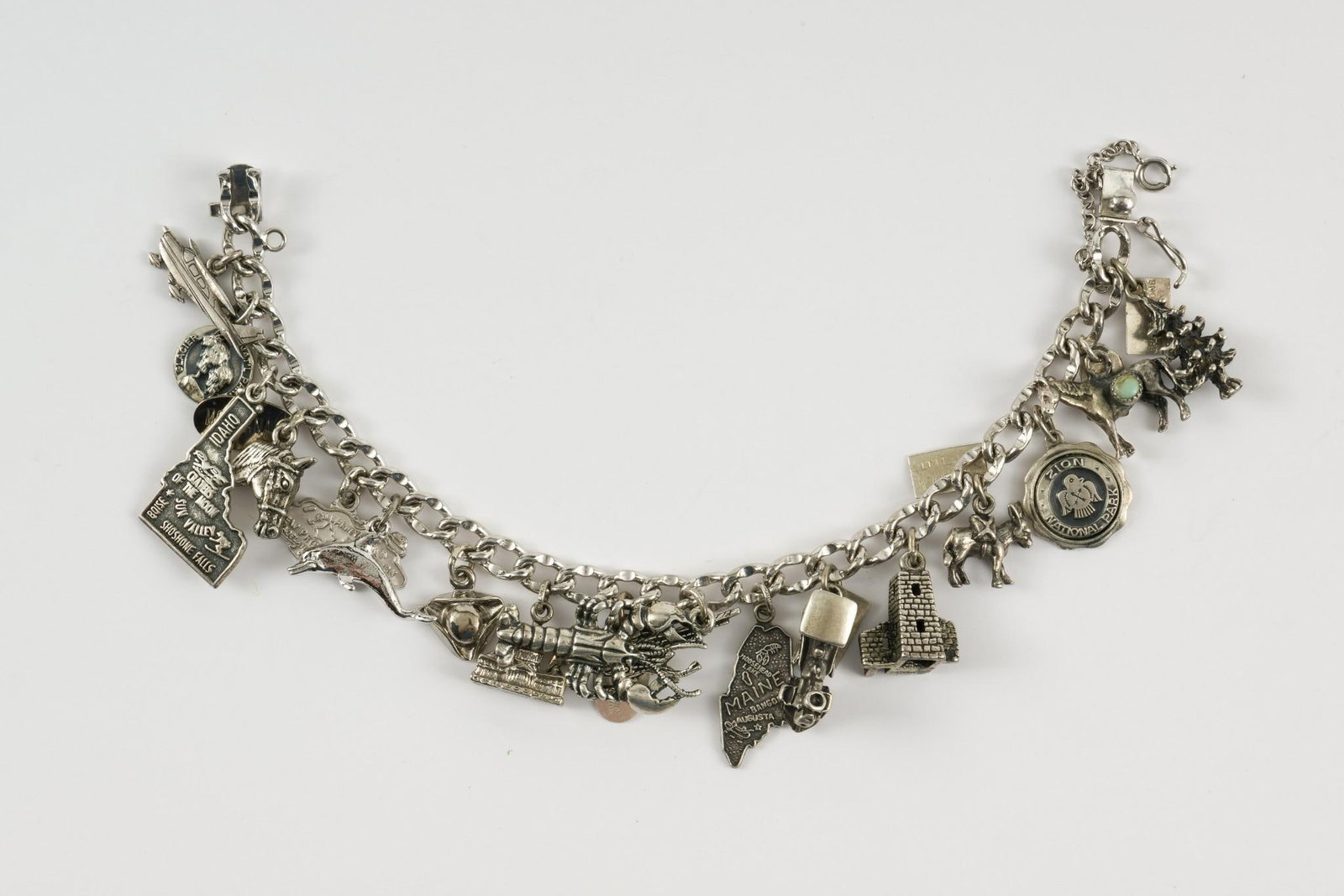 Sterling Charm Bracelet: Sterling charm bracelet with 17 charms. 1-1/2" wide x 7-1/4" long. 1.61 ozt. No condition issues. MEG