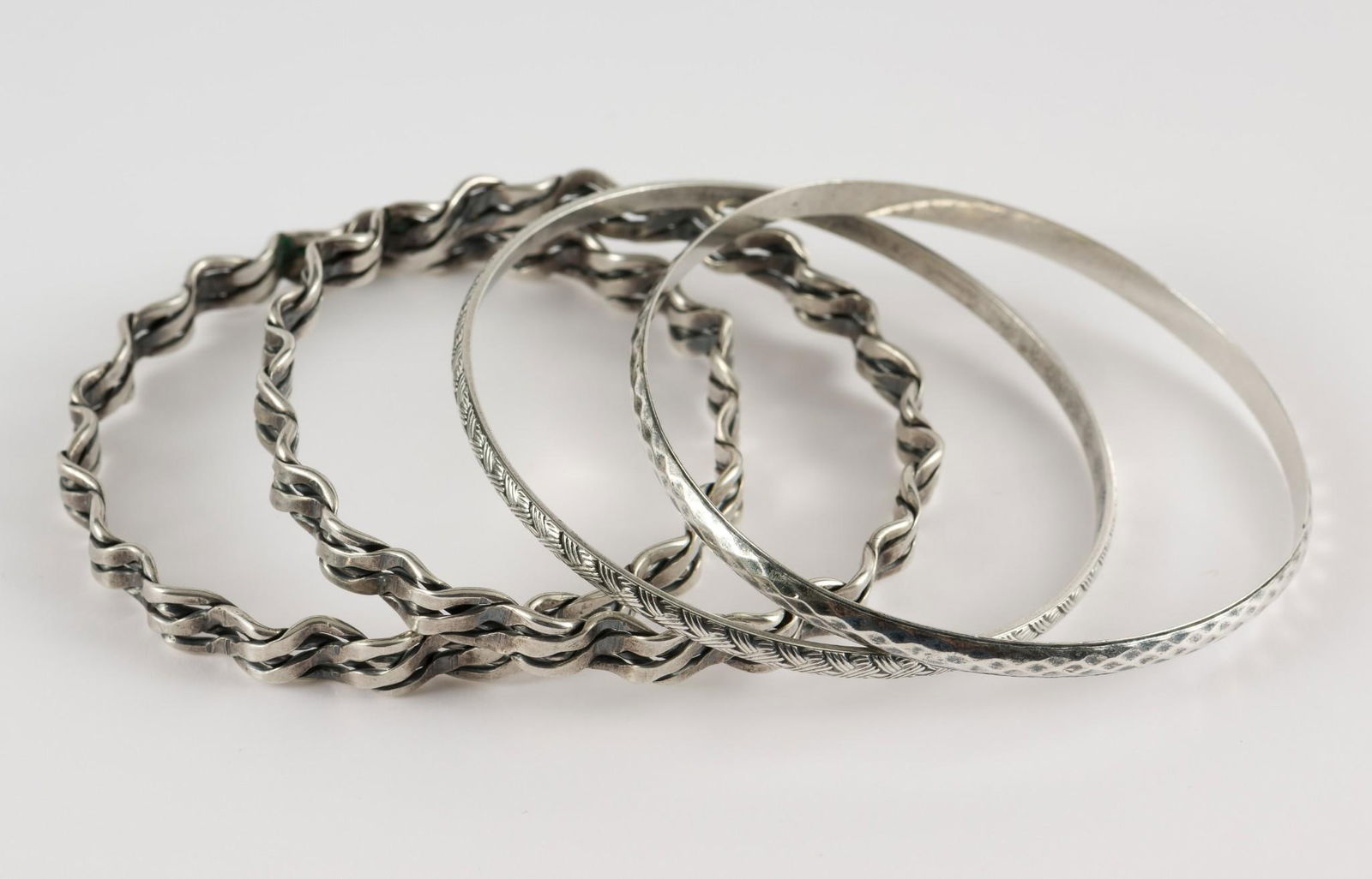 4 Sterling Bangles: Four sterling bangles. All marked sterling. 1/4" to 3/8" wide x 2-1/2" to 2-5/8" diameter. 1.70 ozt total. No condition issues. MEG