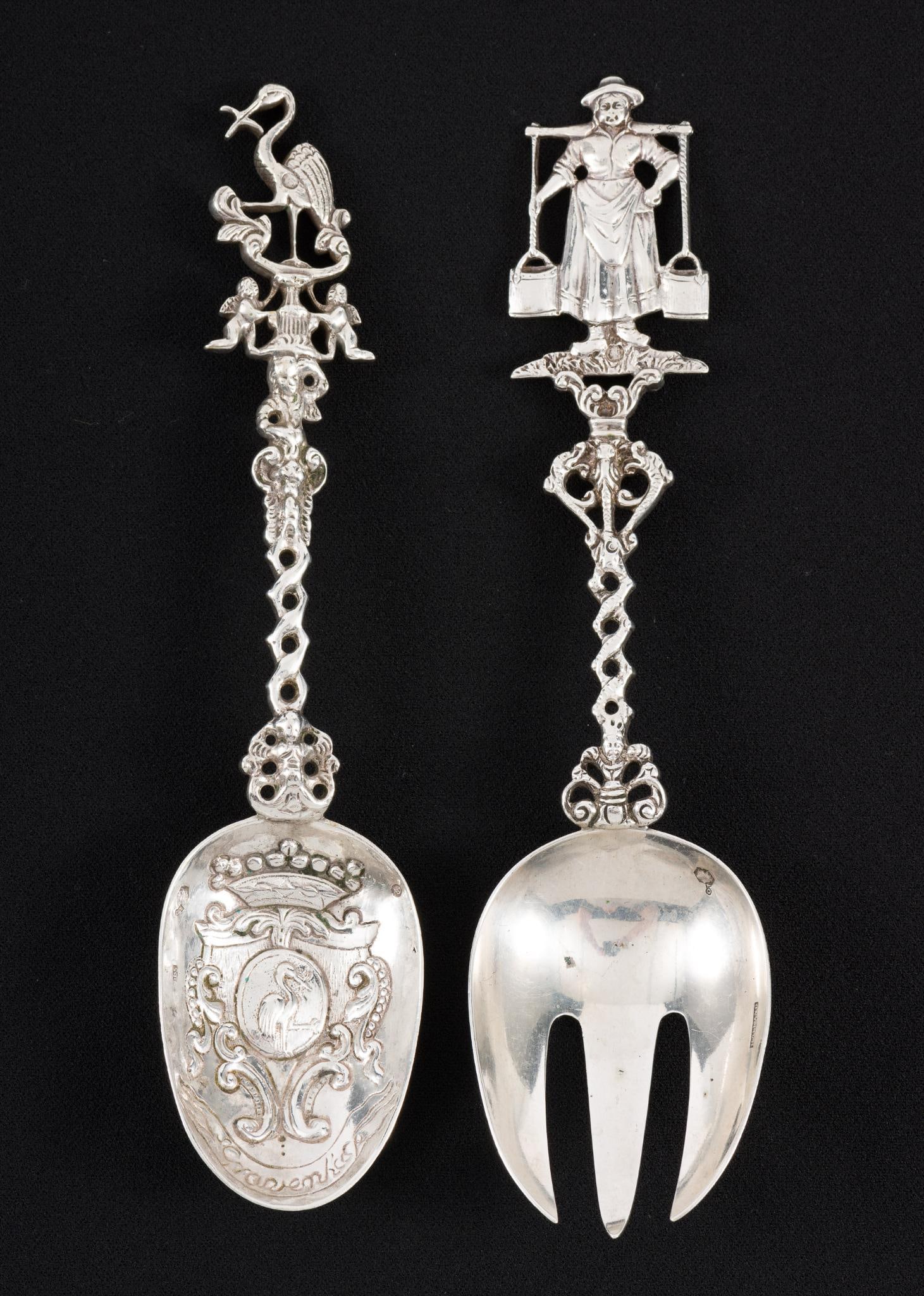 2 Dutch Sterling Silver Dinner Service Pieces: Includes spoon with ornate handle with crane and spork with woman holding buckets on ornate handle. Spork marked Holland. Spoon with Dutch lion hallmark. 4.10 ozt total. 7-3/4" to 8" long. Light scrat