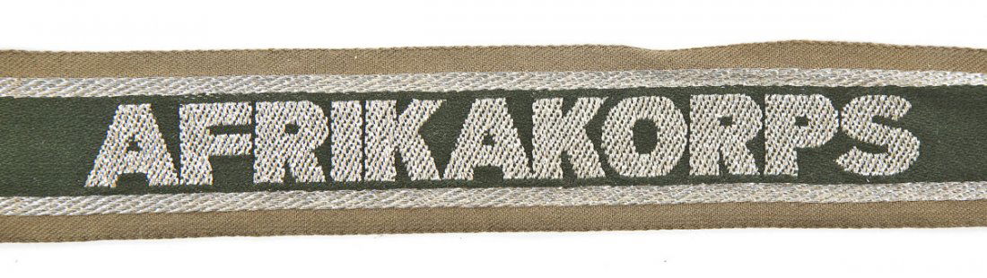 German World War II Army Africa Korps Cuff Title: DESCRIPTION: A German World War II army World War "Afrika Korps" cuff title with bullion wire on green ground. MEASUREMENTS: 18-1/4" x 1-1/4". CONDITION: Wear consistent with age. ESTIMATE: $100 - $20