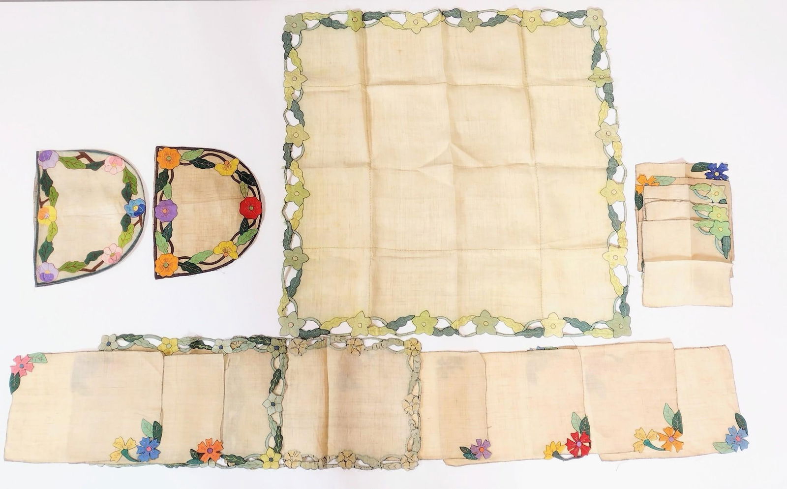 17 Needlepoint and Applique Table Linens: 9-1/2" to 34" wide X 9-1/4" to 33" long. All with discoloration and some losses.