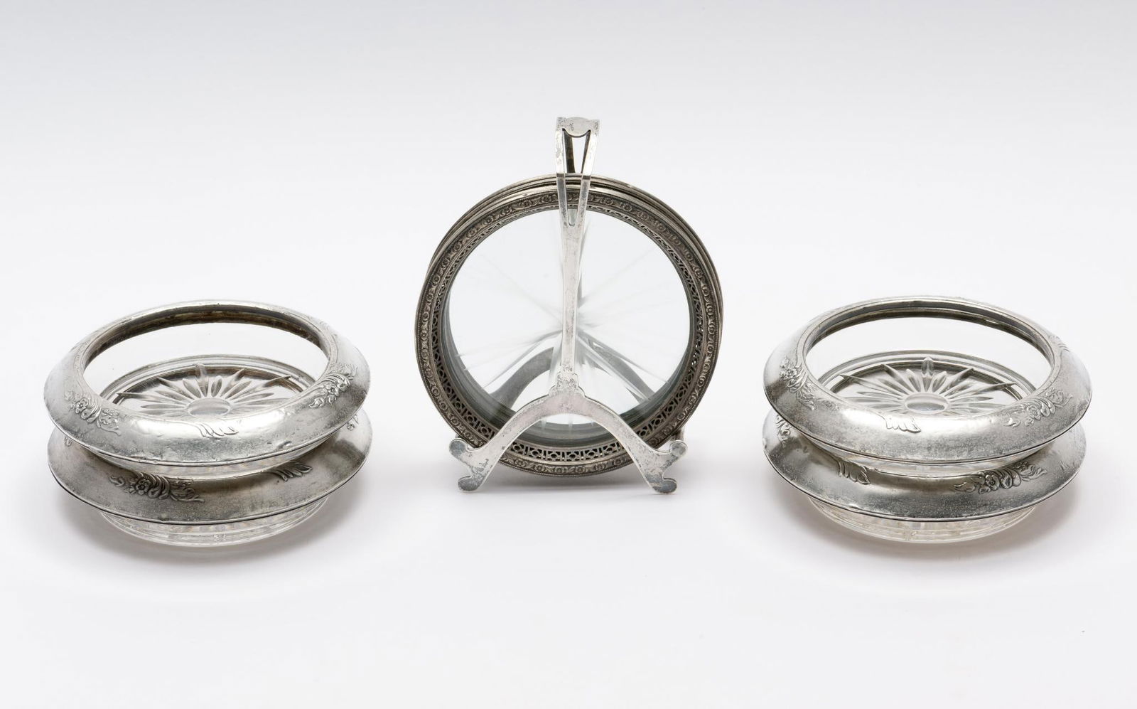 8 Frank M. Whiting Sterling and Glass Coasters: In two sets of four, one set with sterling holder. Marked. Coasters: 3-3/4" to 4" diameter x 1/4" to 3/4" high. MEG