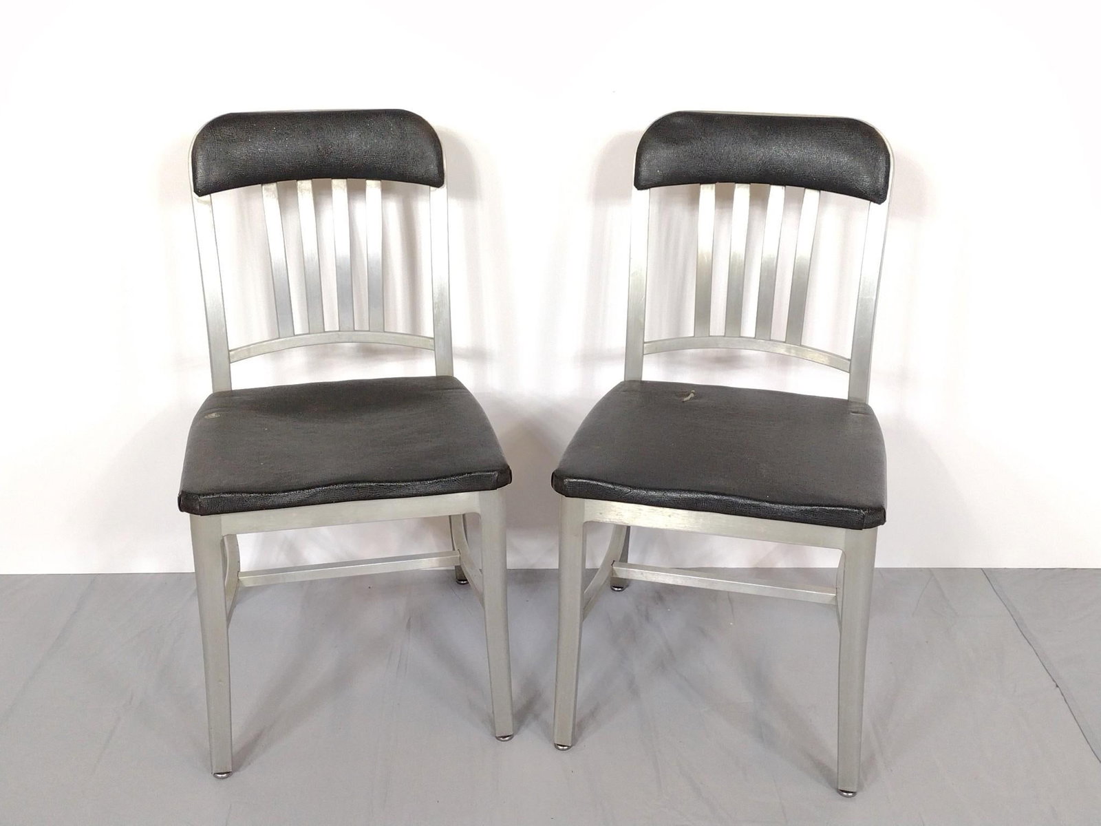 Pair Of Emeco "Submarine" Chairs: NOT ELIGIBLE FOR IN-HOUSE SHIPPING. 17" wide X 19" deep X 33" high. Both have some wear. MG.
