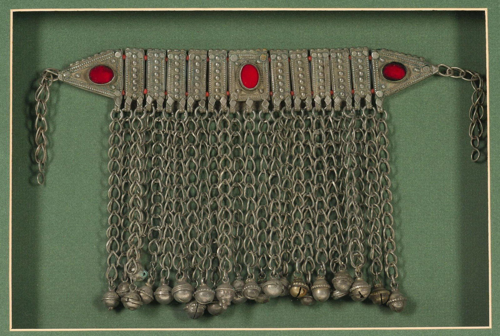 Yemen Silver, Carnelian & Coral Necklace, Framed: NOT ELIGIBLE FOR IN-HOUSE SHIPPING. DESCRIPTION: Bedouin choker necklace with triangular ends, set with carnelian and strung with coral beads, adorned with silver bell dangles. Displayed in frame. MEA