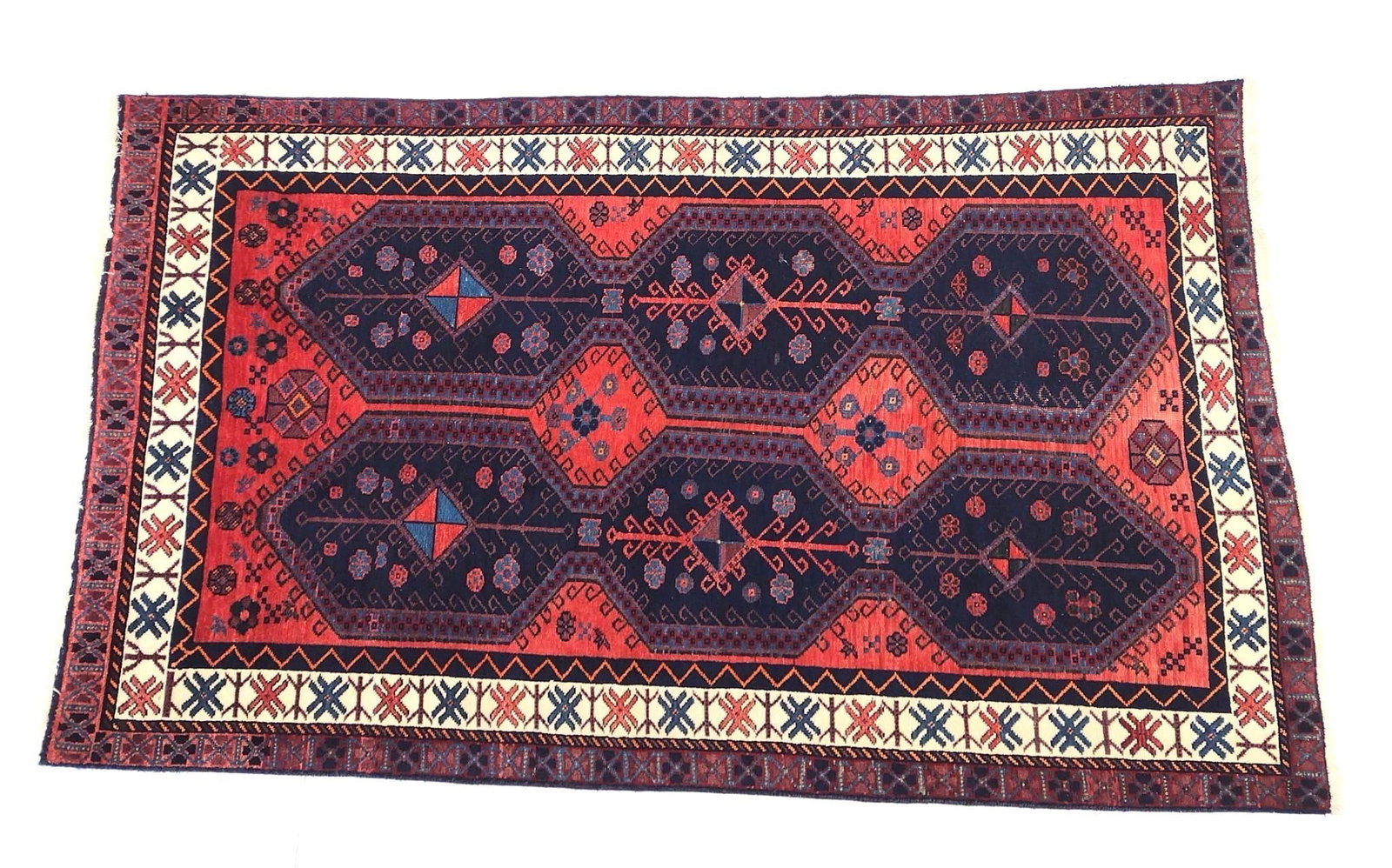 Vintage Persian Rug: NOT ELIGIBLE FOR IN-HOUSE SHIPPING. Circa 1980s. Tribal pattern set in a red field with blue and white highlights. 8' long X 4'10" wide. PROVENANCE: From the Estate of James L. Stanfield, Veteran Nati