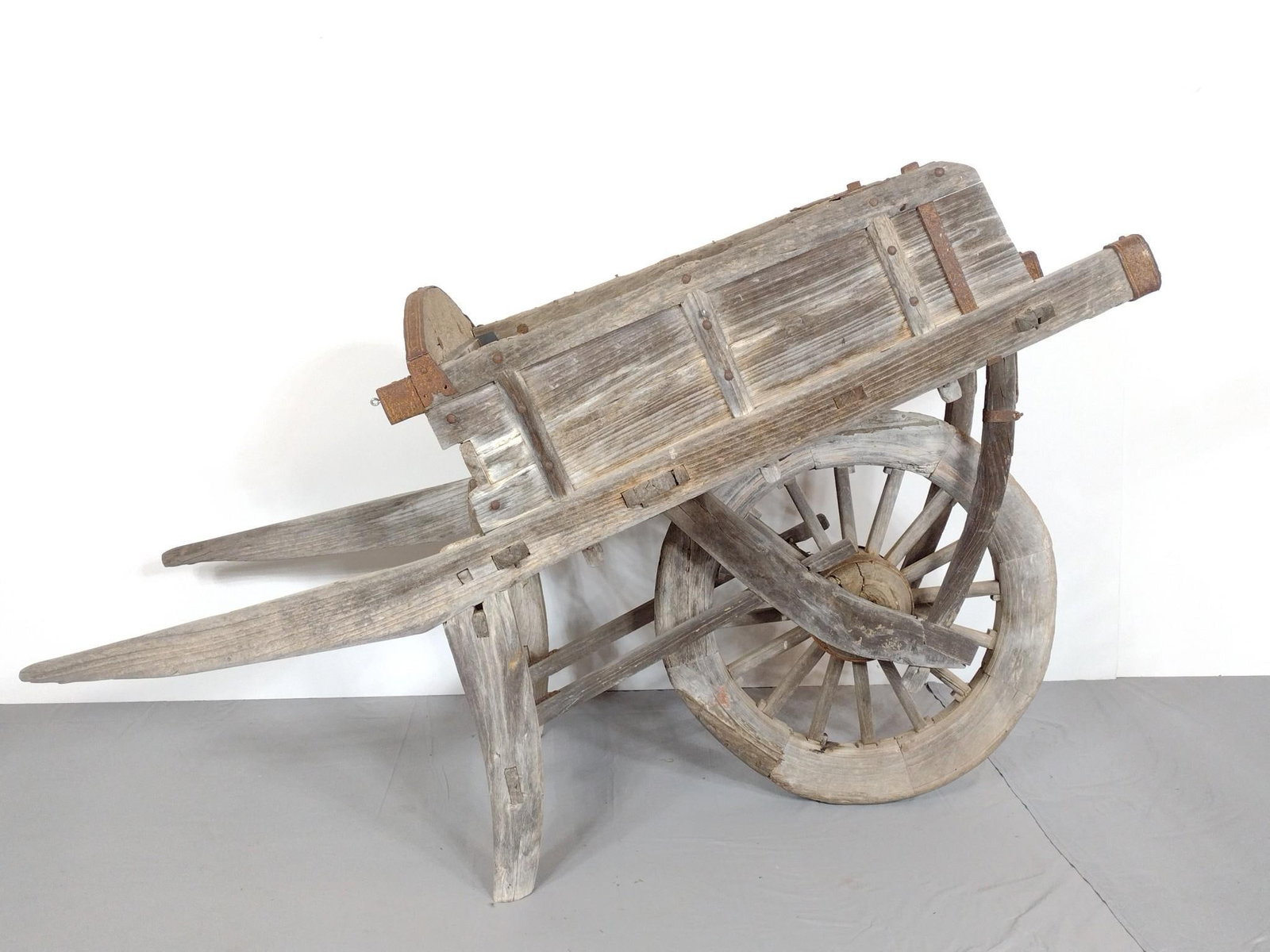 Antique Wheelbarrow: NOT ELIGIBLE FOR IN-HOUSE SHIPPING. 26-1/4" wide X 64" deep X 40-1/2" high. Has repair to front wheel. PROVENANCE: From the Estate of James L. Stanfield, Veteran National Geographic photographer (1937