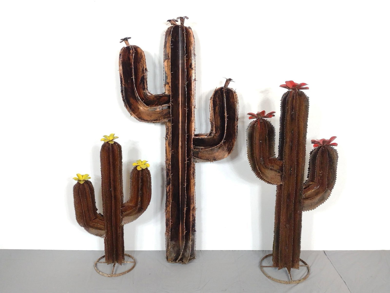 3 Metal Cacti Yard Scluptures: NOT ELIGIBLE FOR IN-HOUSE SHIPPING. From 15-1/2" wide X 27-1/2" high to 23" wide X 50-1/2" high. All have some weathering. PROVENANCE: From the Estate of James L. Stanfield, Veteran National Geographi