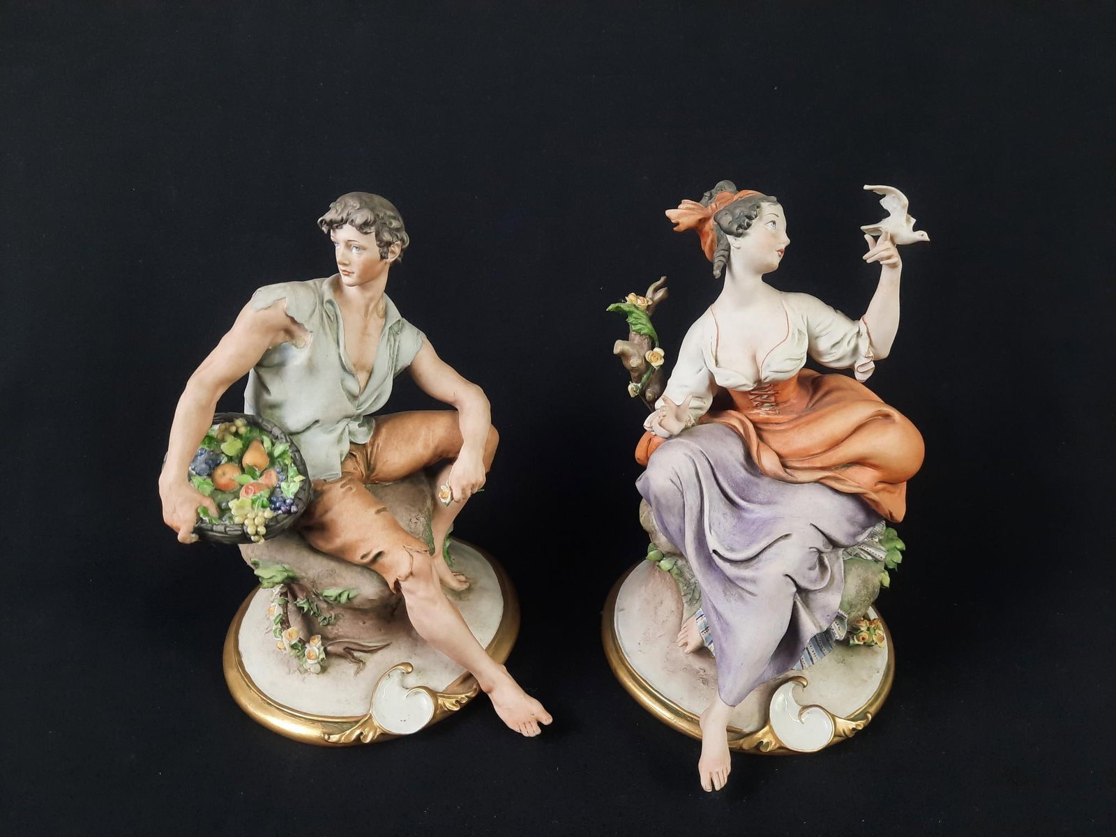 Pr of G. Calle Capodimonte Lover Figurines: Each approximately 6" wide x 7" deep x 8" high. Missing one bird wing and leaf from woman figurine. Both with wear consistent with age and use.