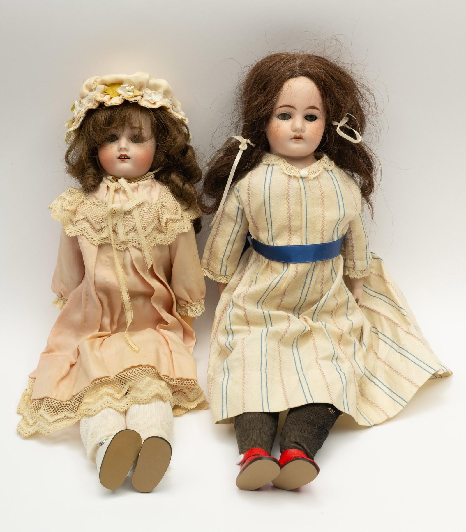 2 Antique German Dolls: 16" to 17-1/2" long. Doll with pink dress: losses to one hand. Both with general wear consistent with age and use.
