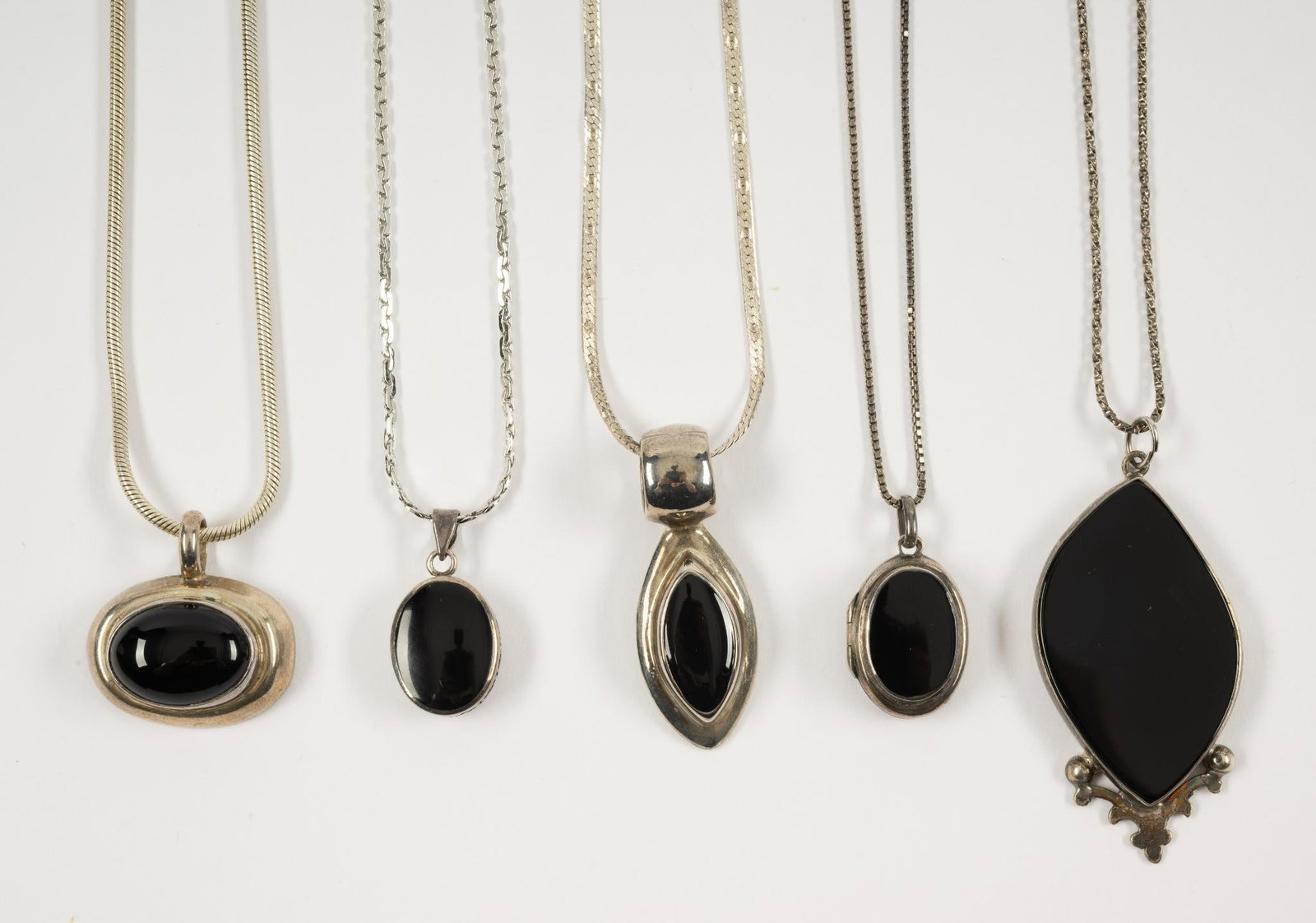 5 Sterling & Onyx Pendant Necklaces: Pendants and chains all marked 925 or sterling. Pendants 1" to 2-1/4", one is a locket. Chains 16" to 28" long.