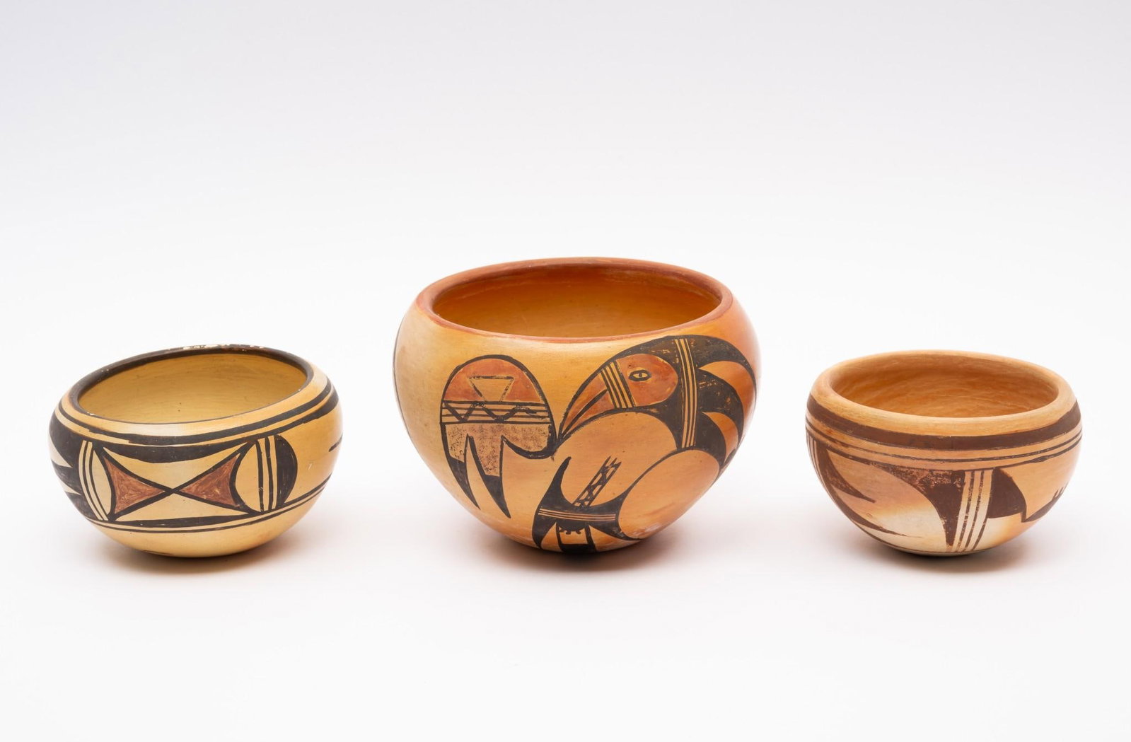 Group of Three Hopi Pots: A group of three Hopi pots, all mid 20th century. The first a geometric low bowl with the mark of a standing deer on the base. The second a lovely thin walled bowl with stylized bird and geometrics si