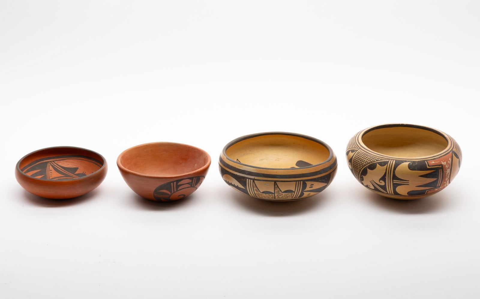 Four Hopi Pots: Four similar Hopi pots. Three unmarked and the fourth signed indistinctly with an image of what appears to be a wasp or hornet. Two of the pots with red clay ground and two with the more typical tan o