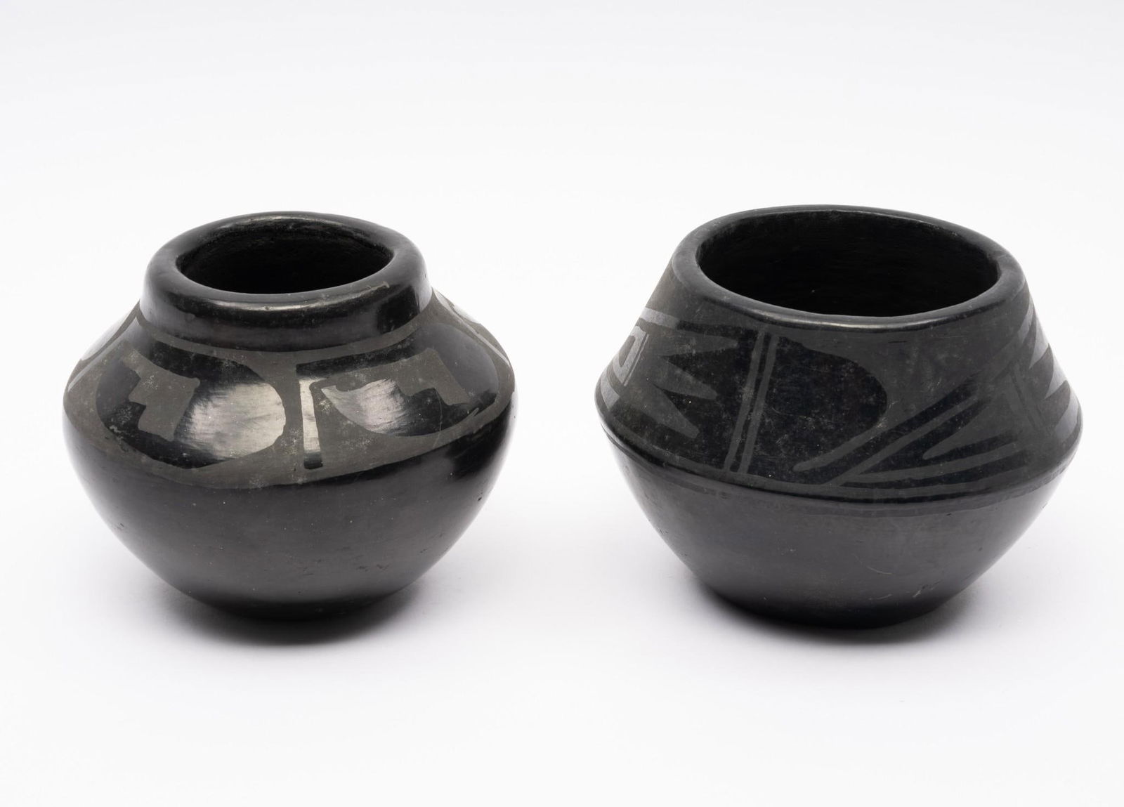 2 San Ildefonso Blackware Pots: The first a San Ildefonso burnished blackware pot that appears to be signed "Lucy Montoya."The second pot, also from San Ildefonso, with illegible signature. Measurements: 2-1/2" to 3-1/2". Condition: