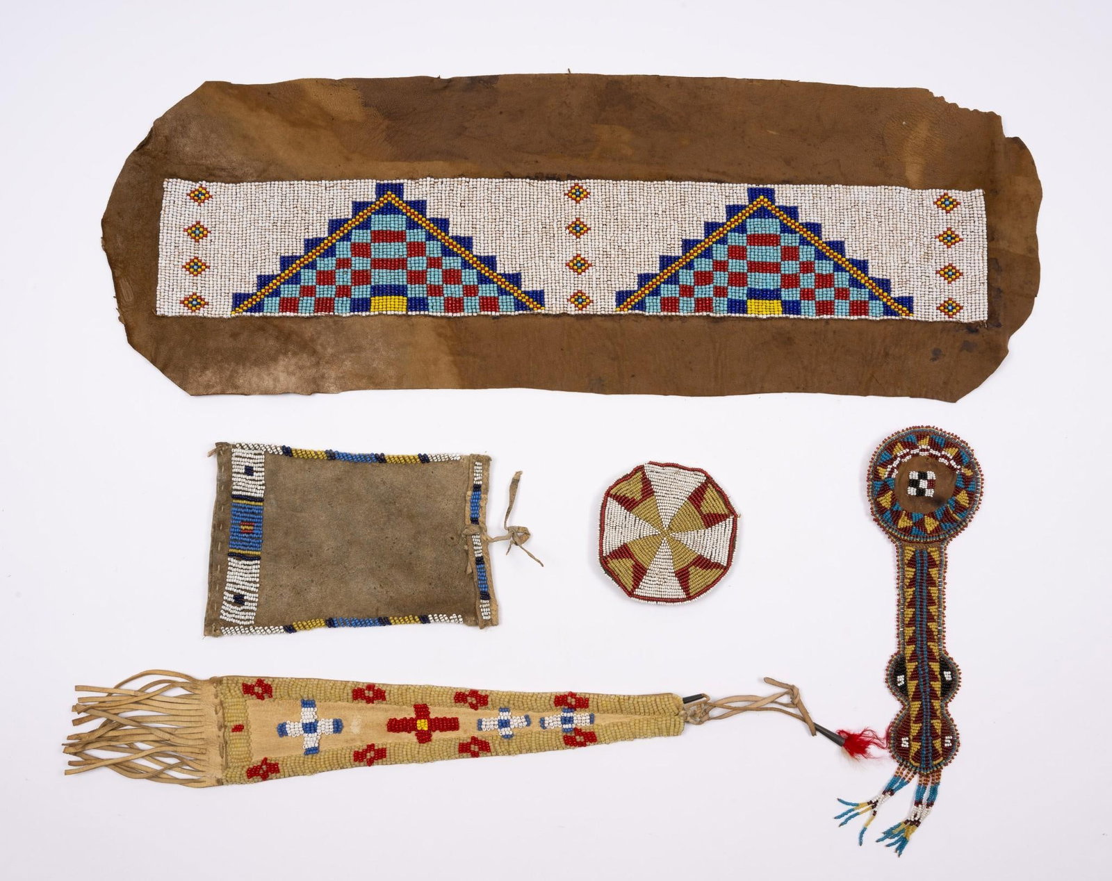 5 Northern Plains Beaded Objects: A group of early 20th century beaded objects. Mostly Northern Plains tribal. Of particular note is the fine awl case probably Sioux. Also a fine beaded blanket strip now attached to a piece of hide. A