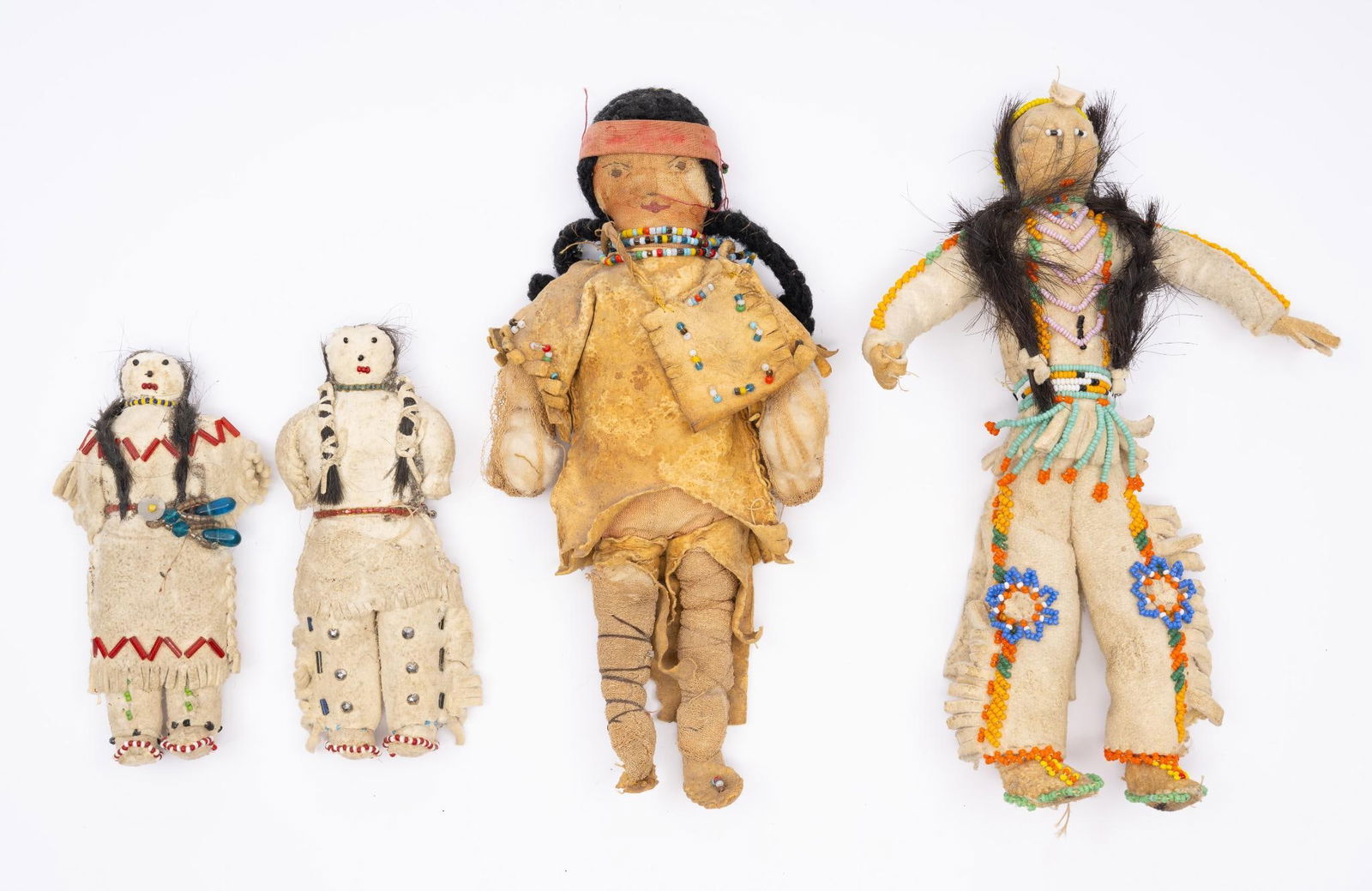 4 Beaded Trade Dolls: A group of four beaded trade dolls. All appear to be mid-western or plains origin. The tall doll with human hair appears to be copied from a male dance costume. Early to mid 20th century. Measurements