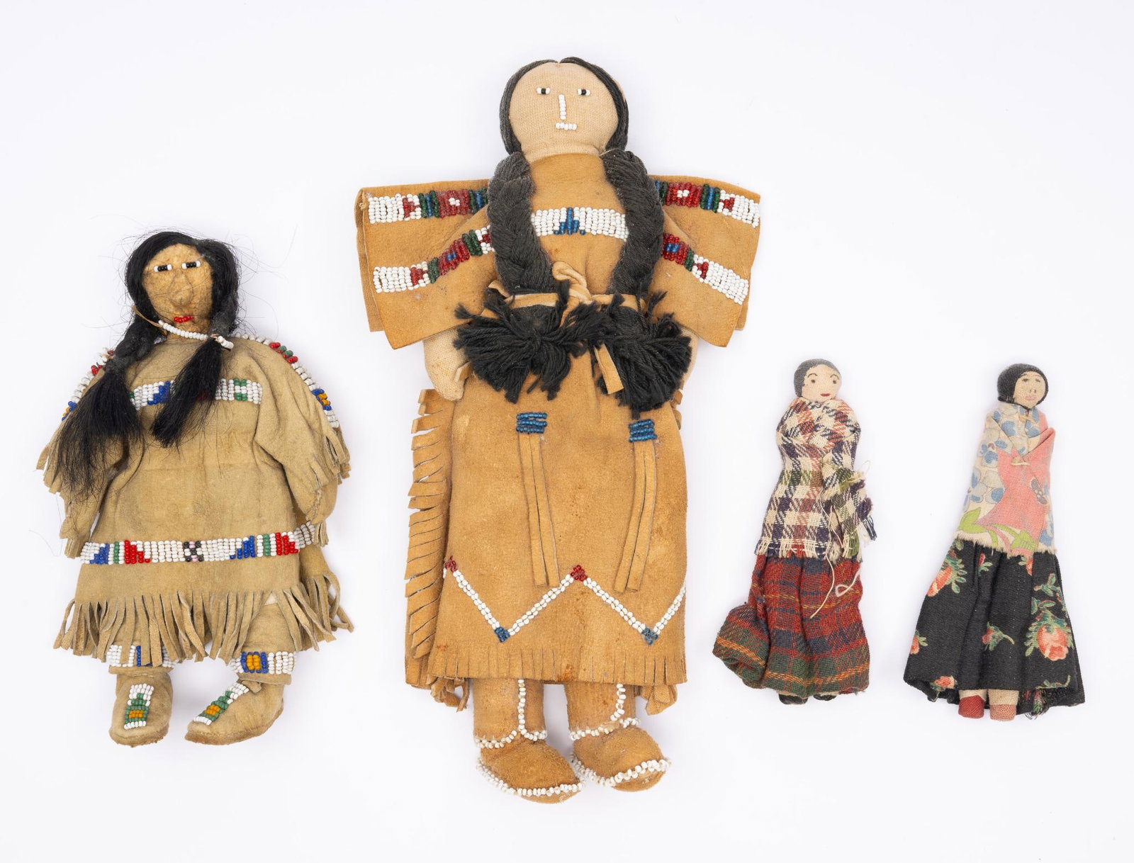 4 Trade Dolls-Sioux and Southern Plains: A group of four trade dolls consisting of two large Sioux hide dolls with human hair and beadwork probably mid 20th century. The other two possibly southern Plains tribal dolls in calico cloth. Measur