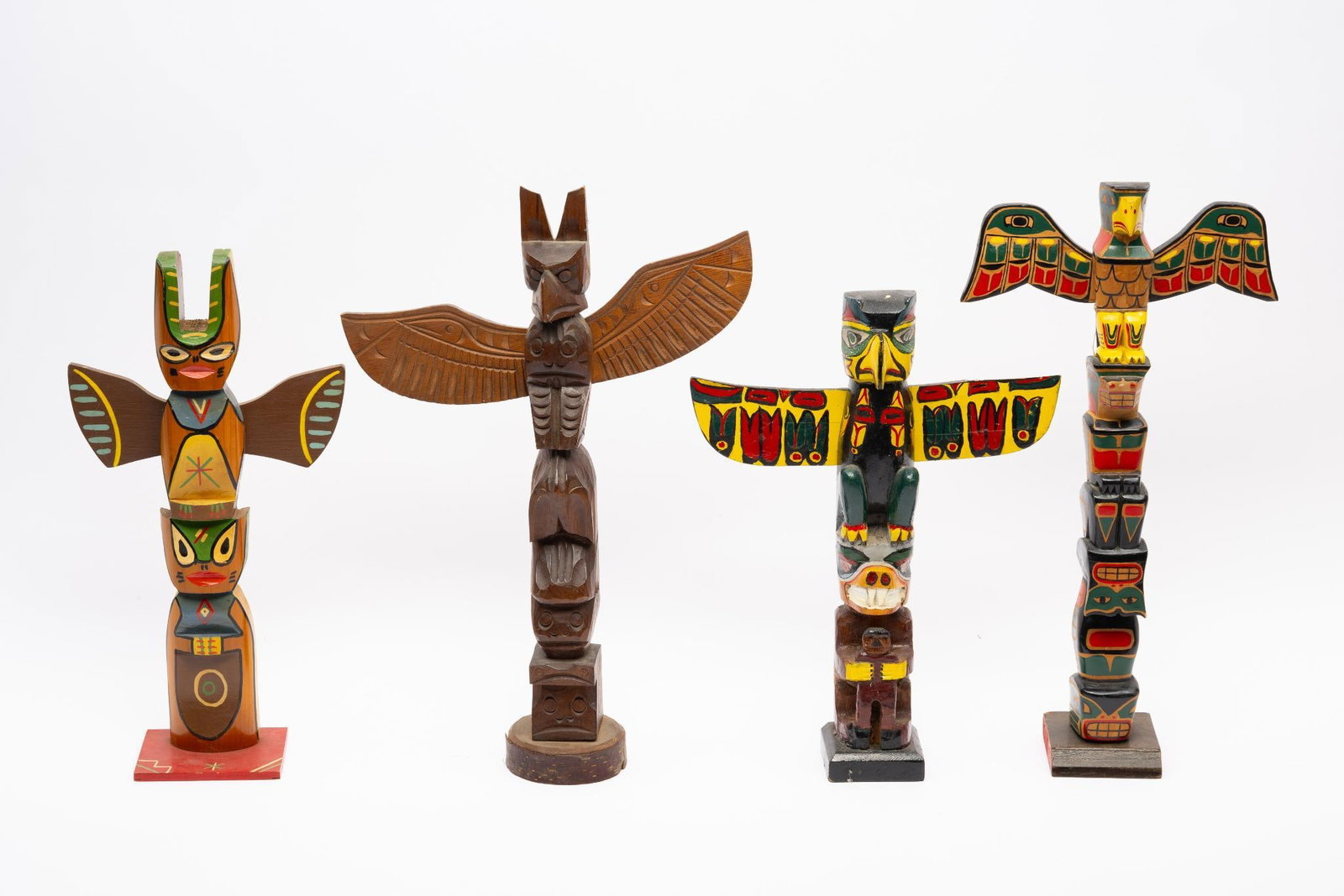 4 Pacific Northwest Tribal Totem Poles: Four Pacific Northwest Tribal totem poles. One natural wood and the remaining three polychrome. Circa 1960-1990 approx. Measurements: 11" to 16" tall. Condition: Overall good.