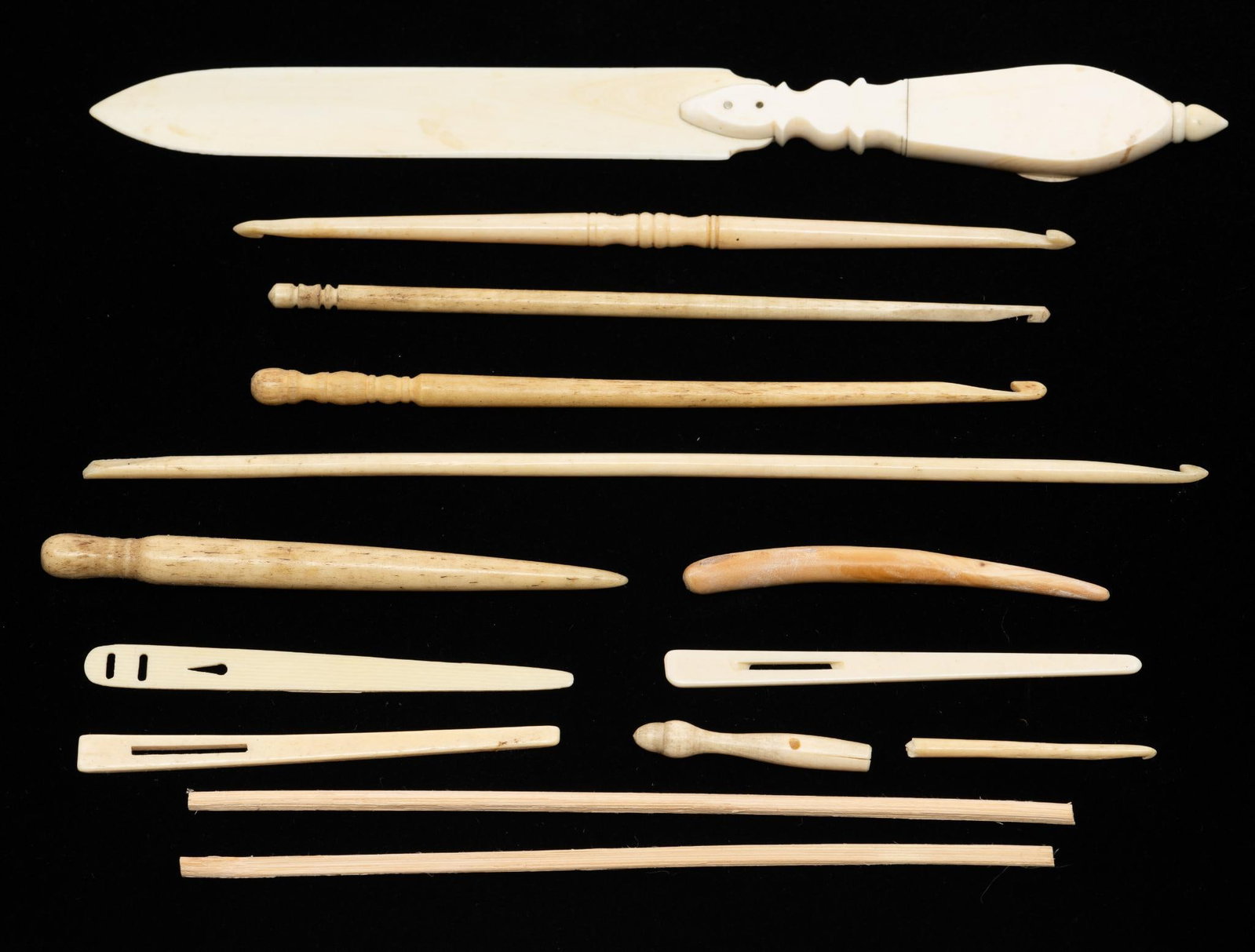 13 Inuit or Athabaskan Bone Carvings: A collection of thirteen Inuit or other Arcitic tribally produced carvings including net weaving tools, sewing implements and souvenir items such as letter openers. Early to mid 20th century. Measurem