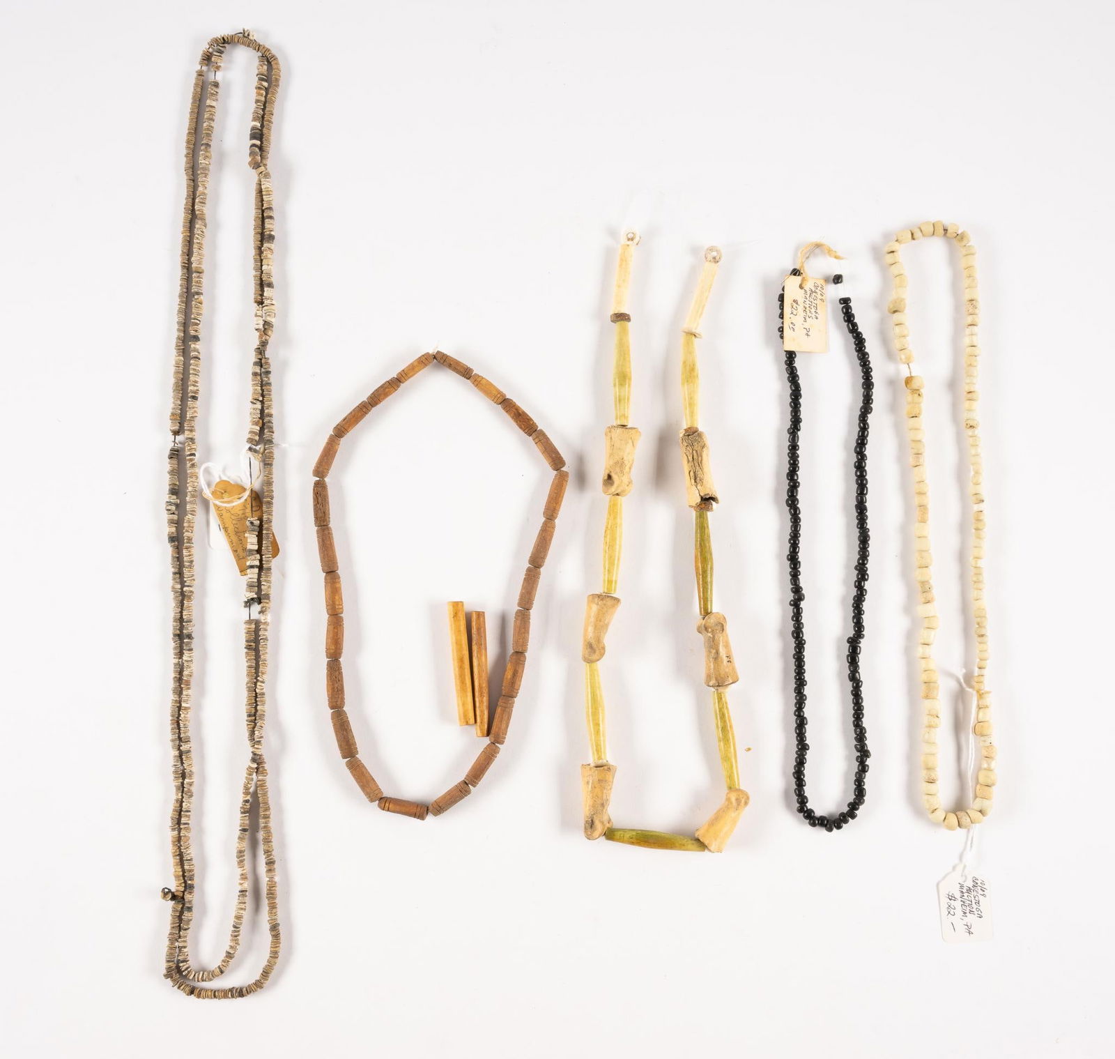 5 Beadwork Pieces: Deer Bones and carved stone beads necklace with tag noting from collection of the Lenape Museum. Also includes trade and carved native discoidal beads probably Eastern Woodlands. One strand has a tag