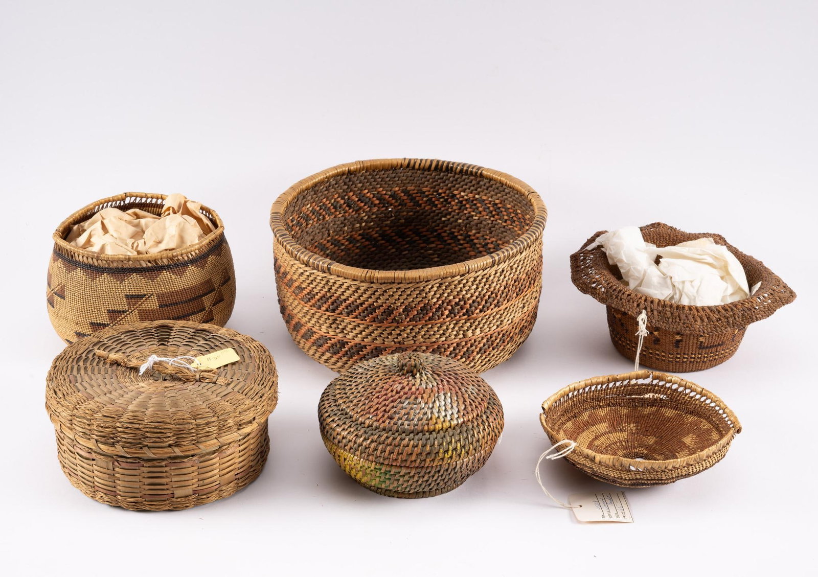 5 Tribal Baskets: A group of five tribal baskets, many with damages, including Eastern Woodland, Western Apache and Pacific coastal. Measurements: 6-1/4" to 10" diameter. Condition: Some deterioration, but overall good