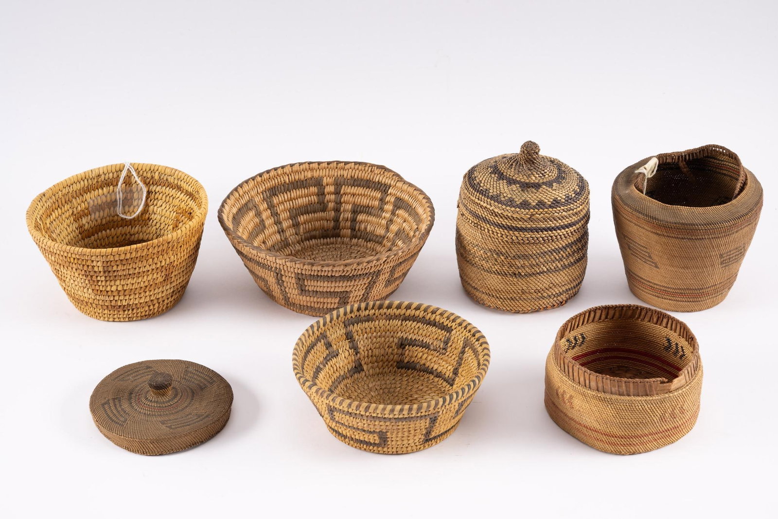 6 Tribal Baskets Incl Pima: Six tribal baskets consisting of three Greek Key Pima baskets and three additional including Pacific Northwest. Measurement: 4" to 7" diameter. Condition: Wear consistent with age and rim damage to on