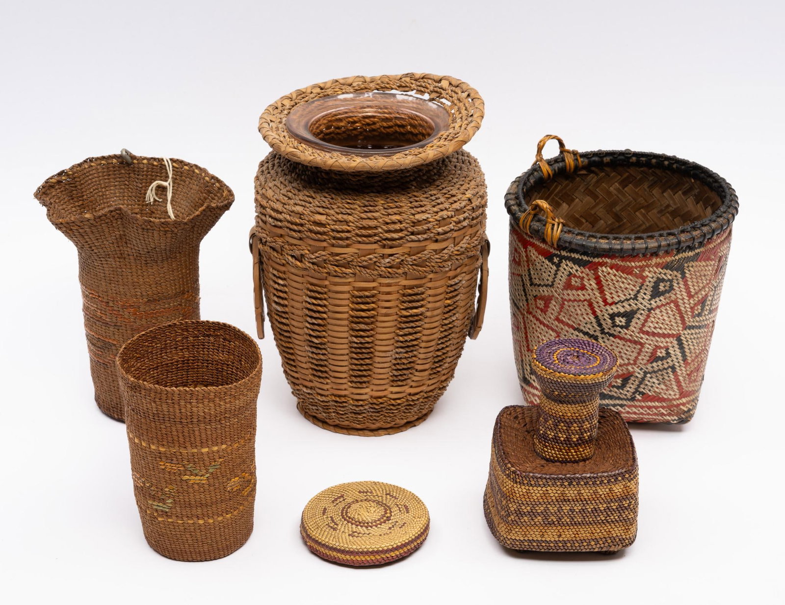 5 Woven Tribal Basket Jars and Vases: A group of five tribal woven baskets in jar and vase form probably late 19th century or early 20th century. Measurements: 3" to 6" diameter. Condition: Vase has glass interior, but overall good.