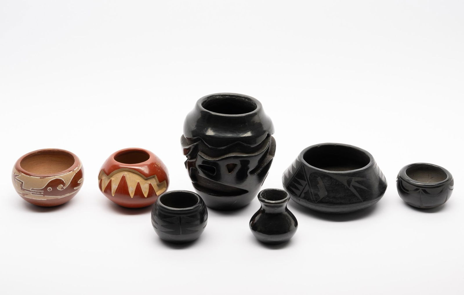 7 pieces of Burnished Black and Red Pottery: A group of seven pieces of blackware and redware pottery from San Ildefonso pueblo consisting of an unsigned Avanyu red pot from Santa Clara, a carved red pot signed Anita Suazo from Santa Clara, an u