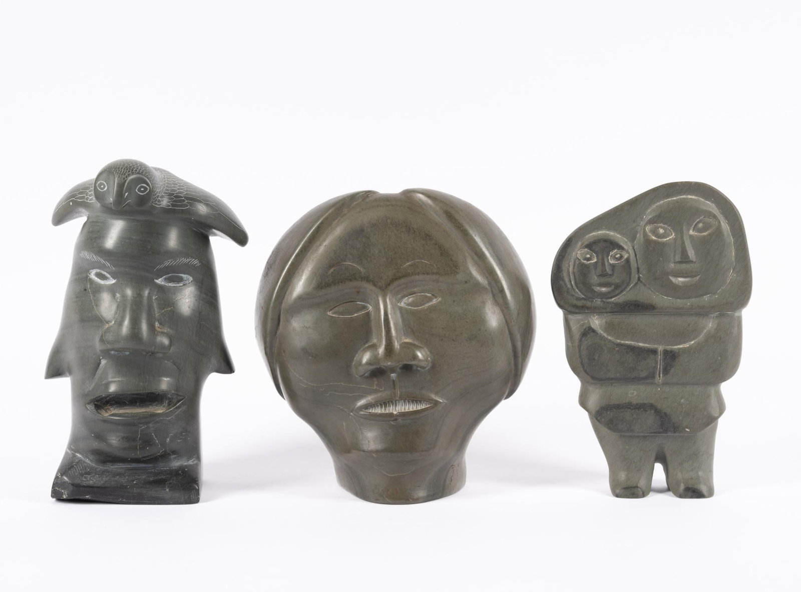 Three Inuit Carved Stone Pieces: All three signed but one not distinctly. Annie Niviaxie Woman And Child 7 1/2", Adamie Papyarluk, head of a woman 7 1/2", owl on the head of a man, indistinctly signed 8 1/4" height.