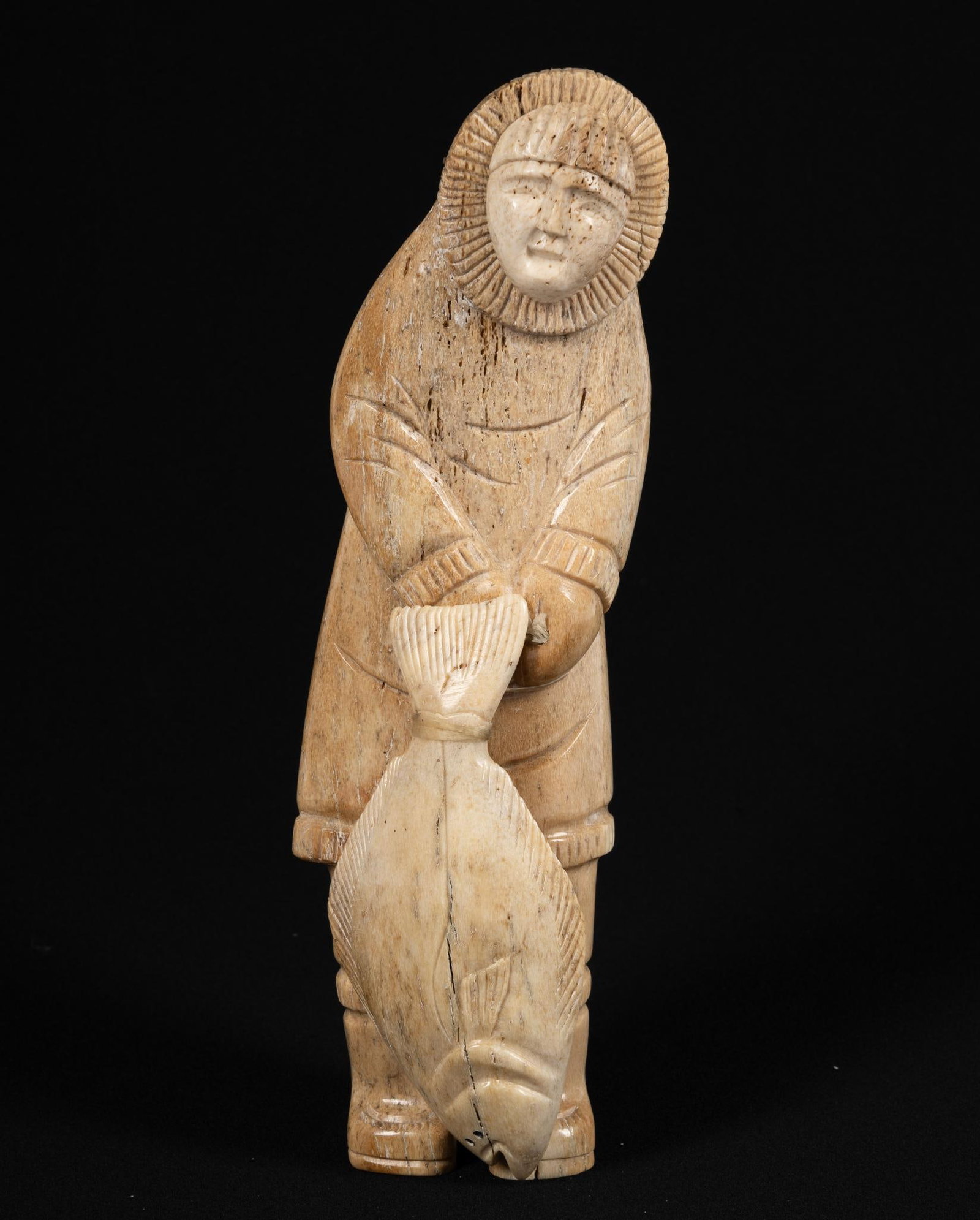 Carved Inuit Fossilized Bone by Chivly Chupak: Inuit hunter with fish by Chivley Chupak, Juneau, AK. Height 9 3/4"