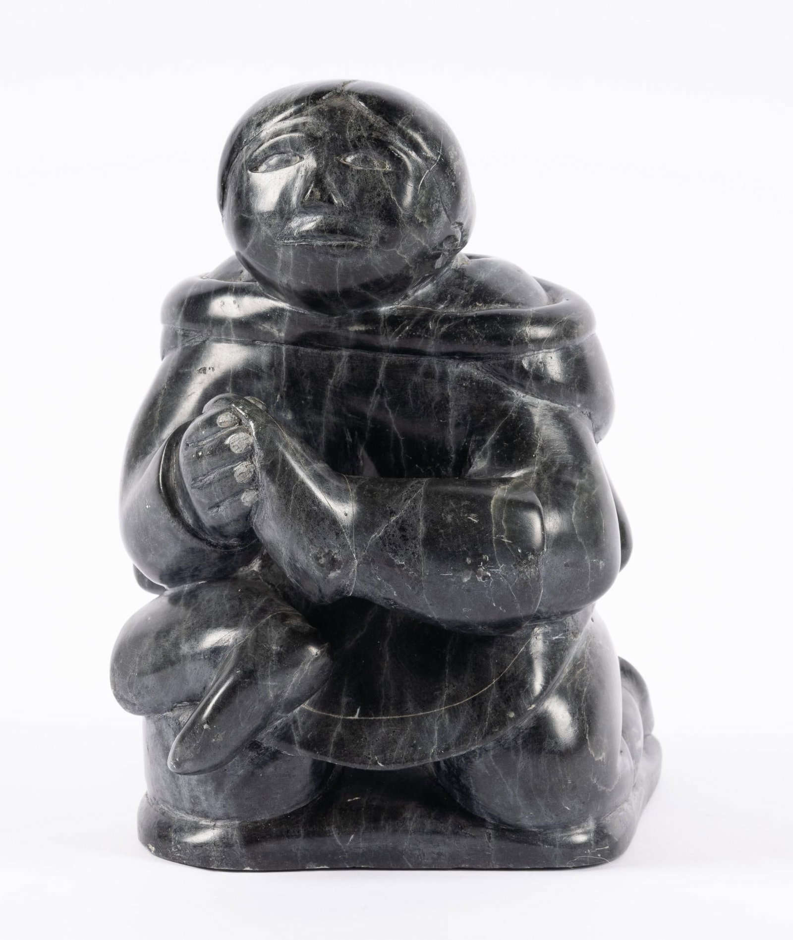 Inuit Carved Stone by Paulosie Sivuak: NOT ELIGIBLE FOR IN-HOUSE SHIPPING DESCRIPTION: Carved black stone, patterned with fracture lines, of Inuit woman holding a kamik. Paulosie Sivuak 1930 -1986. MEASUREMENT: 8 1/4" high.