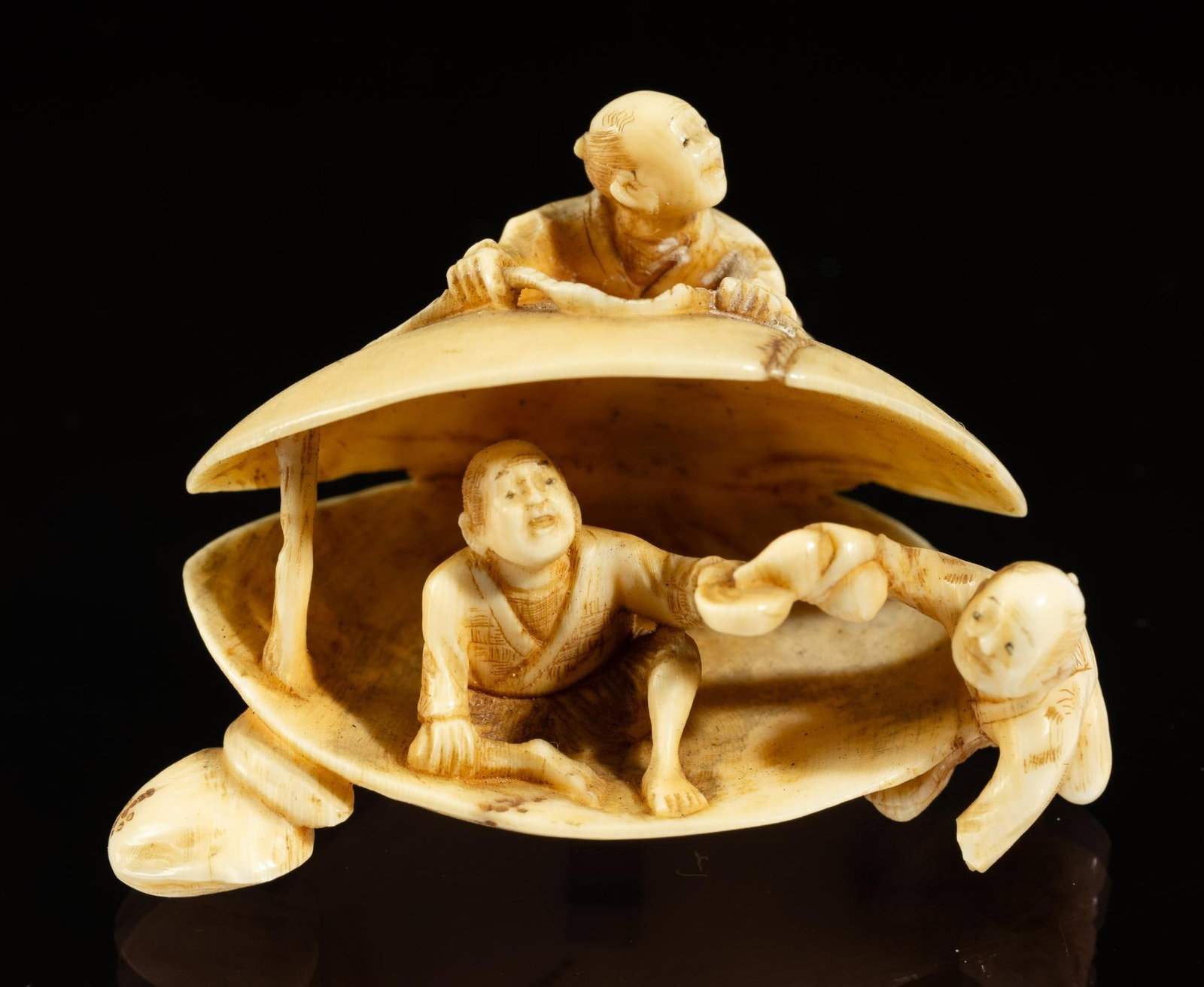 Carved Bone Anabori Netsuke: DESCRIPTION: 19th century Meiji Japanese carved bone Anabori Netsuke. Open clam with a man sitting inside holding a cup, a second man is pouring tea into his cup. A third man is laying on top of the c